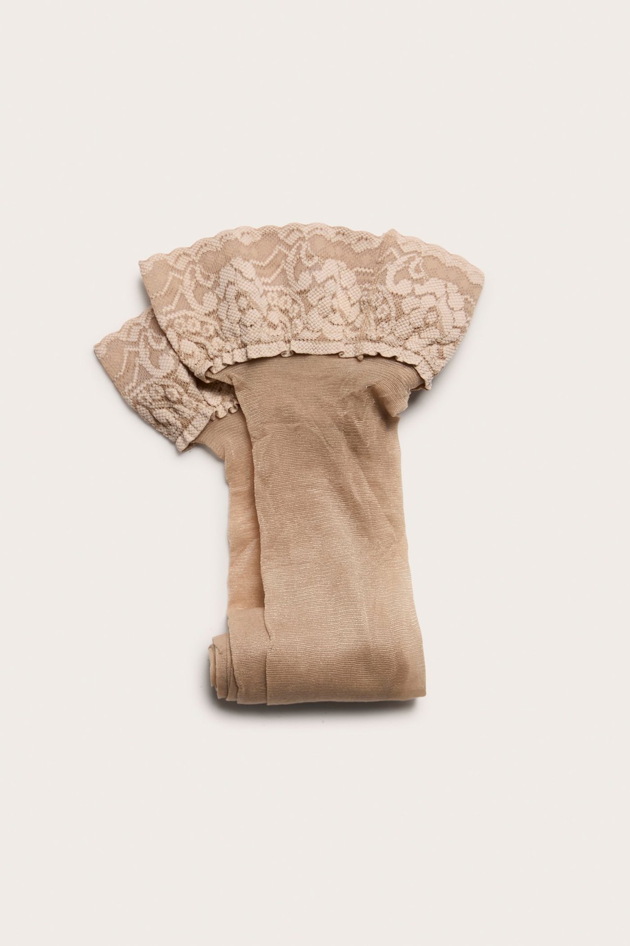 Widok z góry na złożone jasnobeżowe rajstopy stay-up 20 den z szeroką koronkową lamówką.