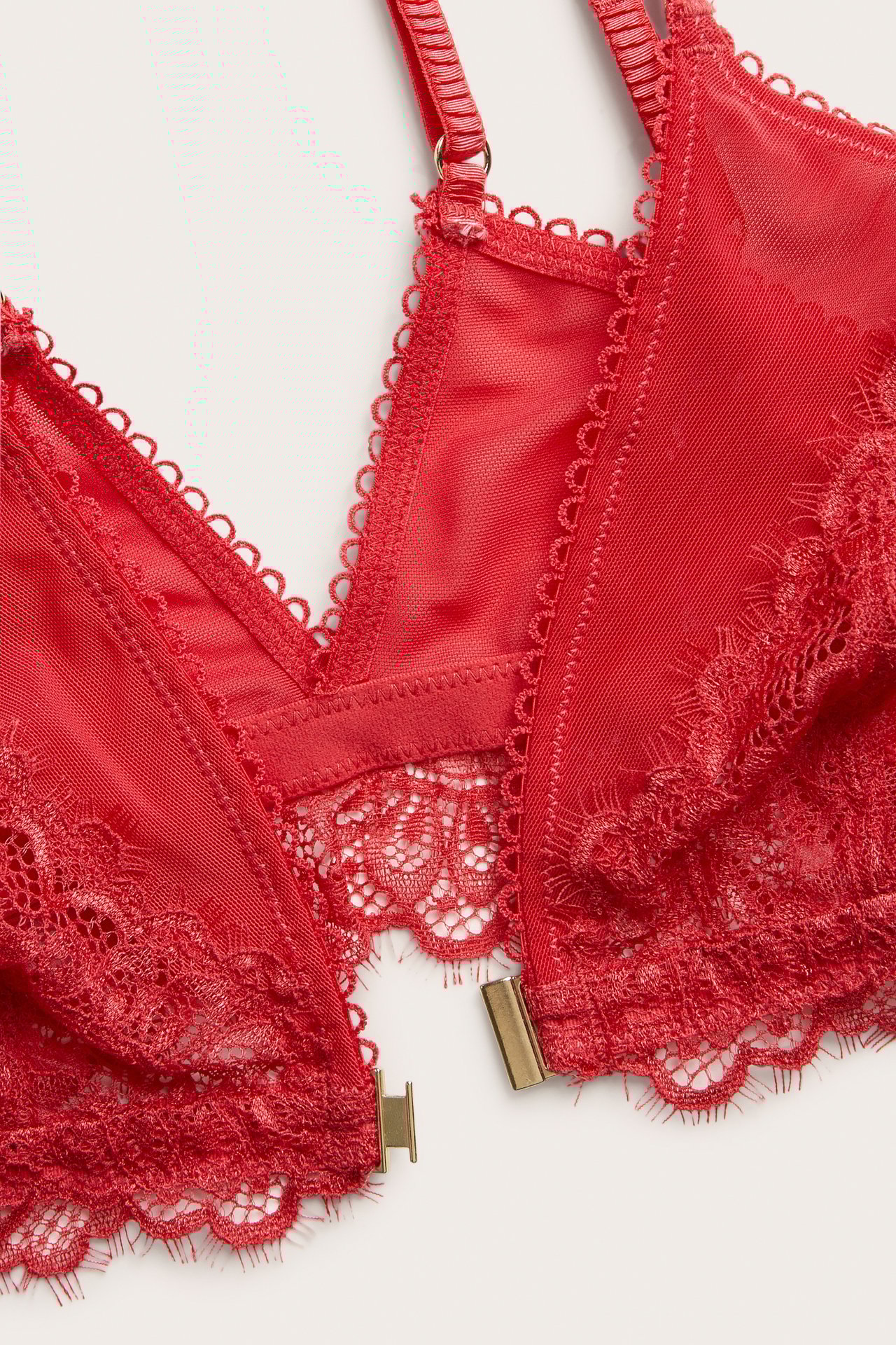 Närbild av en röd ovadderad spets-bh med dubbla band och guldtonad knäppning fram.