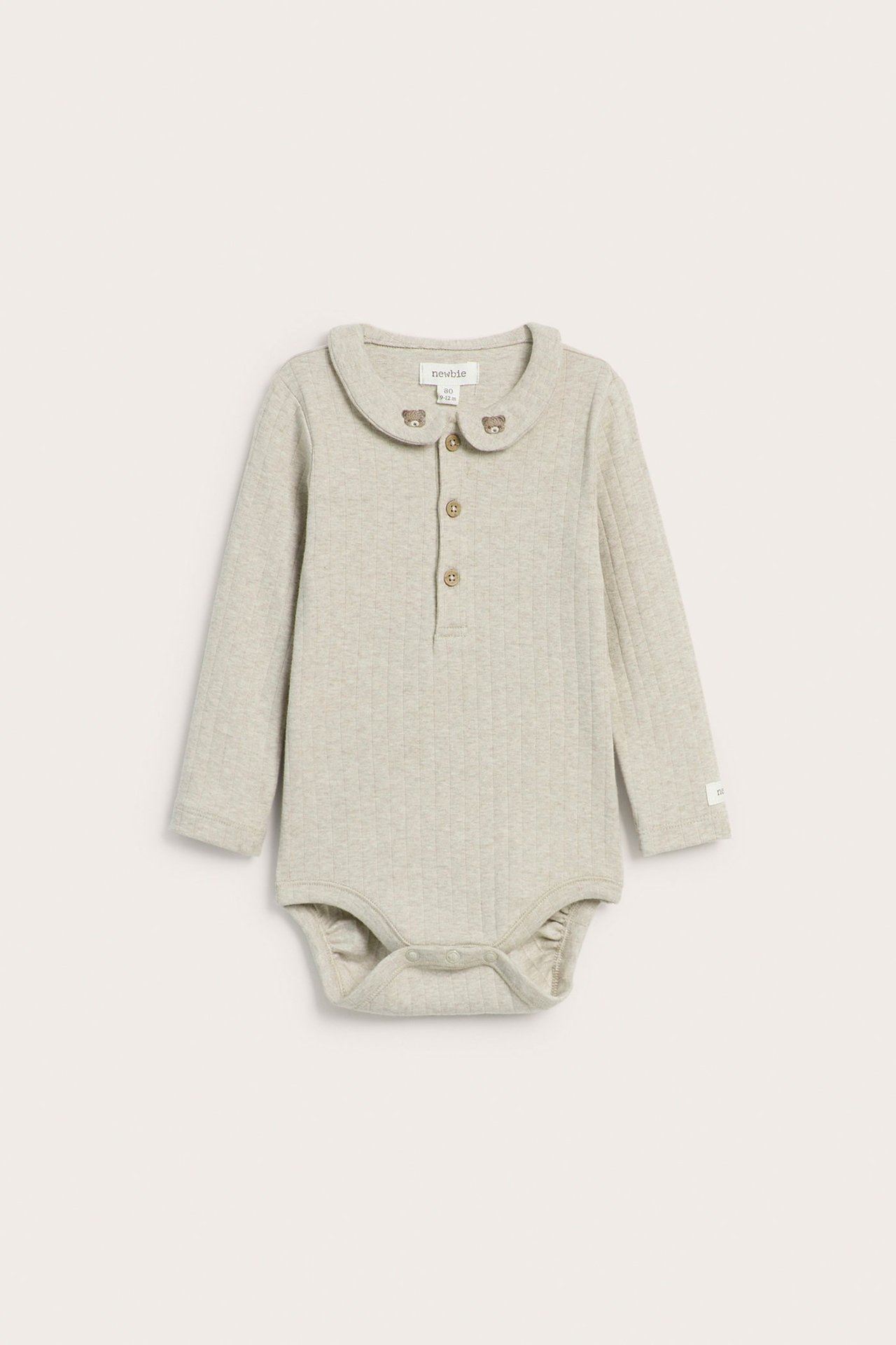 Forfra: beige ribbet babybody med lange ermer, krage med teddybjørn-broderi og knapper foran.
