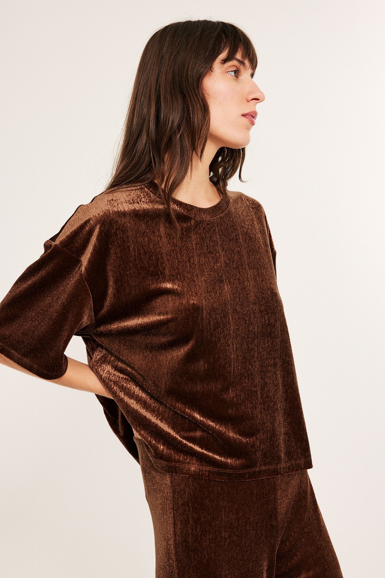 Kvinne i profil som har på seg løs passform velour-topp i brun med korte ermer.