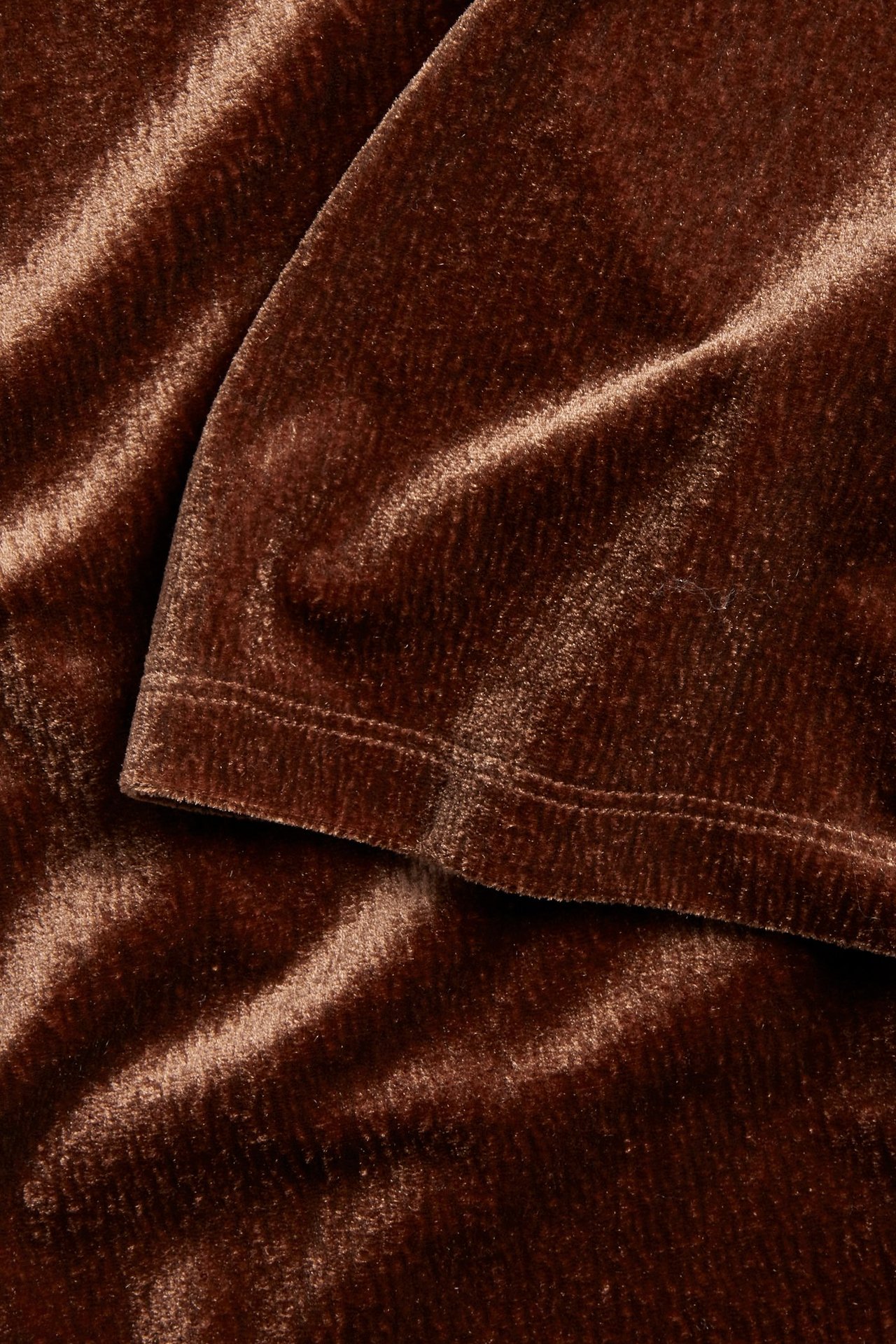 Zbliżenie brązowego, welurowego topu z krótkim rękawem, ukazujące obszyty brzeg.