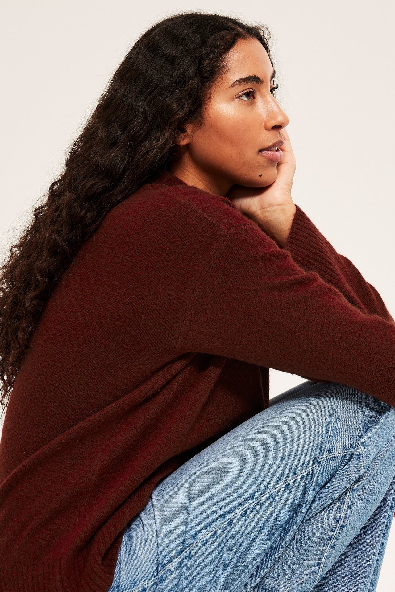 Pehmeä punainen sekoitehuppari, käytössä nainen sivulta, istuen.