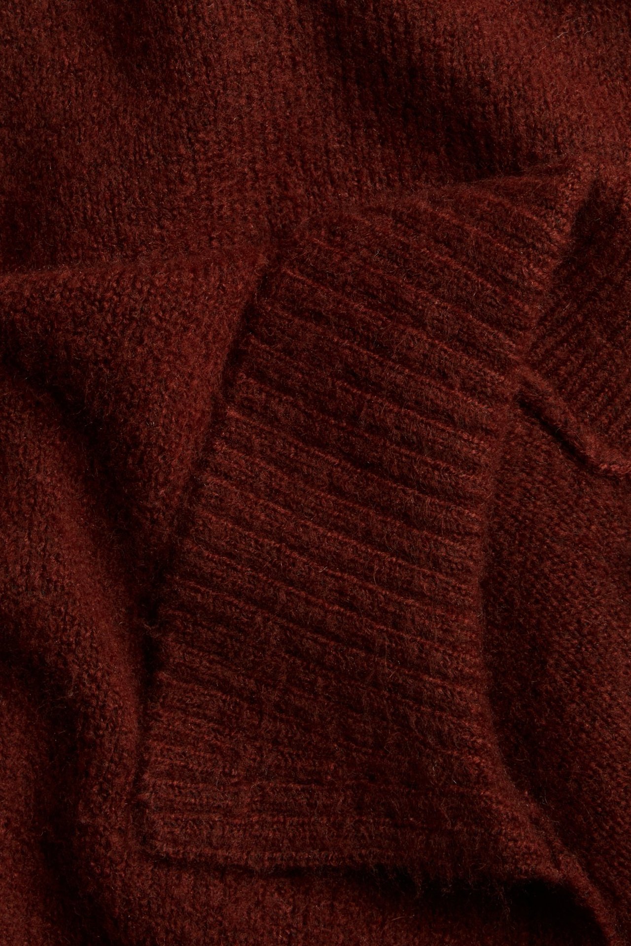 Zbliżenie miękkiego, czerwonego melanżowego dzianinowego swetra z prążkowanym kołnierzem.