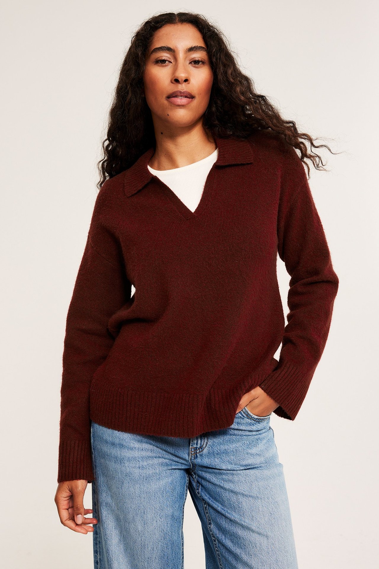 Pehmeä punainen neulospaita kauluksella, raitainen, naisella farkuissa.