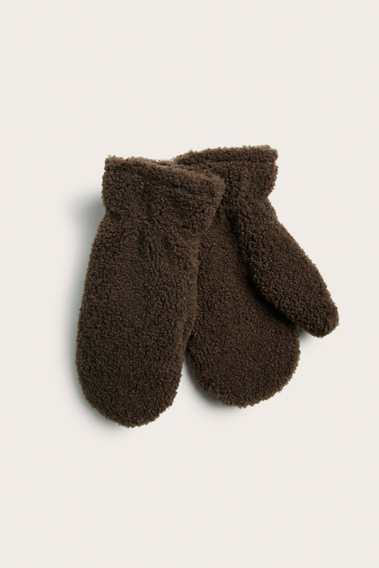 Ylhäältä kuvassa tummanruskeat, yksiväriset teddykankaasta valmistetut lapaset.