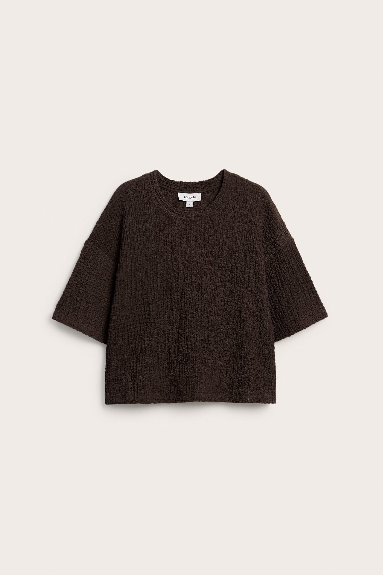 Widok z przodu ciemnobrązowego, obszernego T-shirtu ze strukturalnym wzorem i krótkimi rękawami.