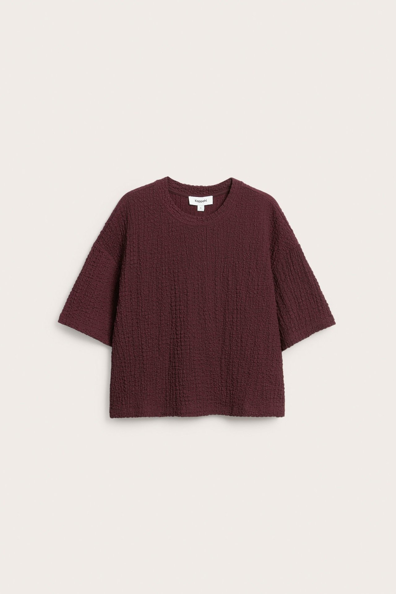 Forfra, mørkerød oversized t-skjorte med strukturmønster og korte ermer.