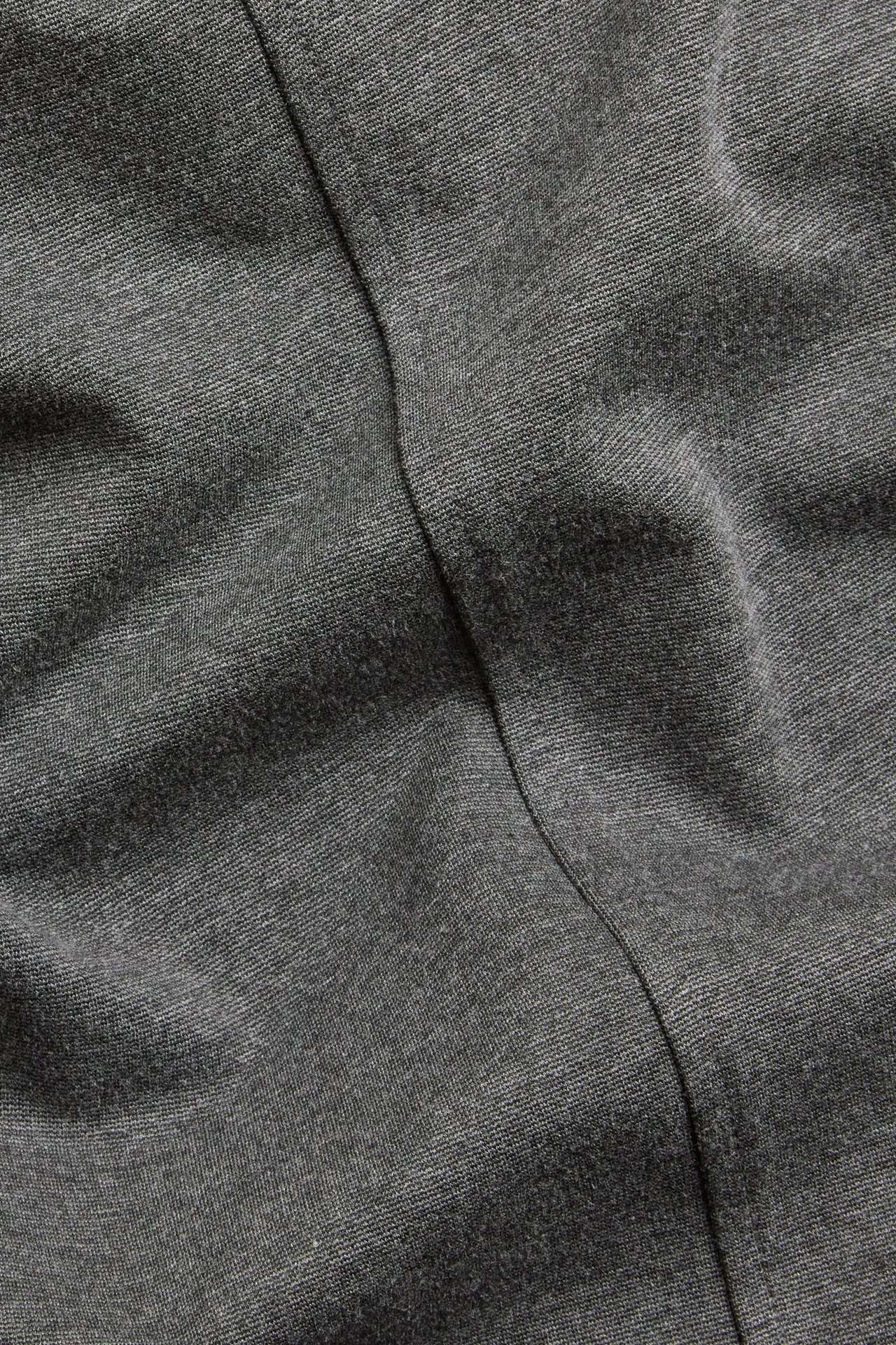 Zbliżenie na ciemnoszary melanżowy materiał krótkiej sukienki z widocznym szwem.