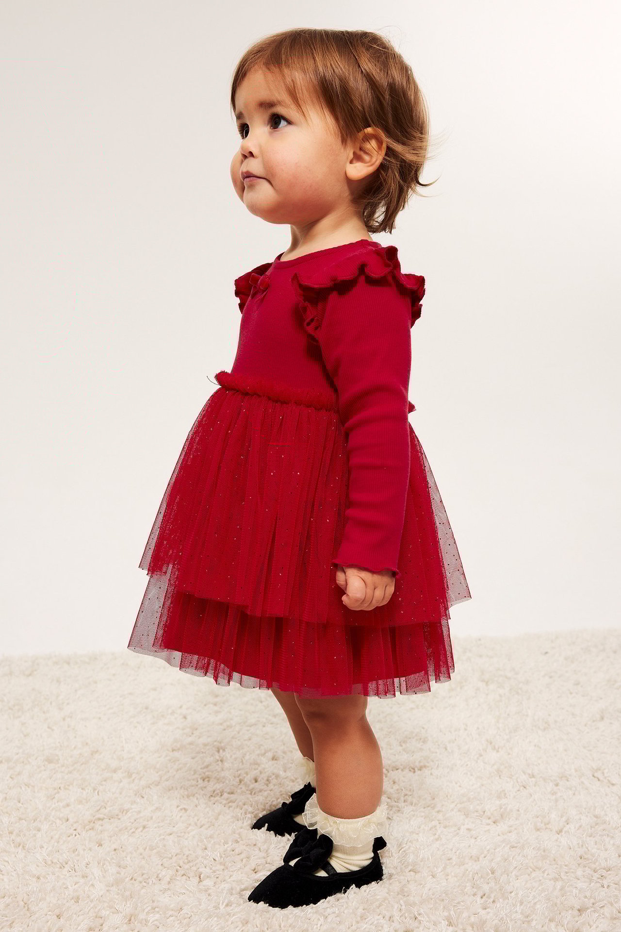 Liten jente i rød julekjole med glitternett, fløyelsbånd, frontvisning.
