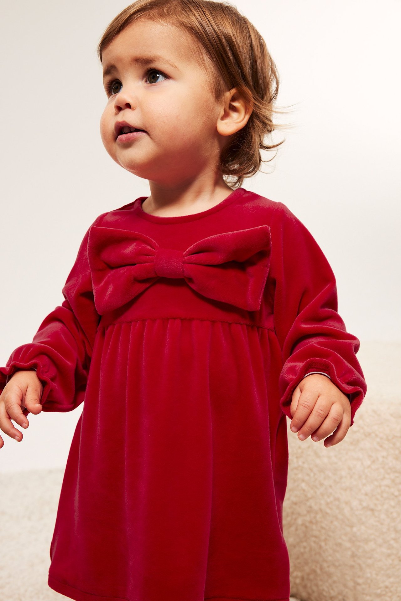 Rød velourkjole til baby med sløyfe foran og knepping i nakken, ensfarget.