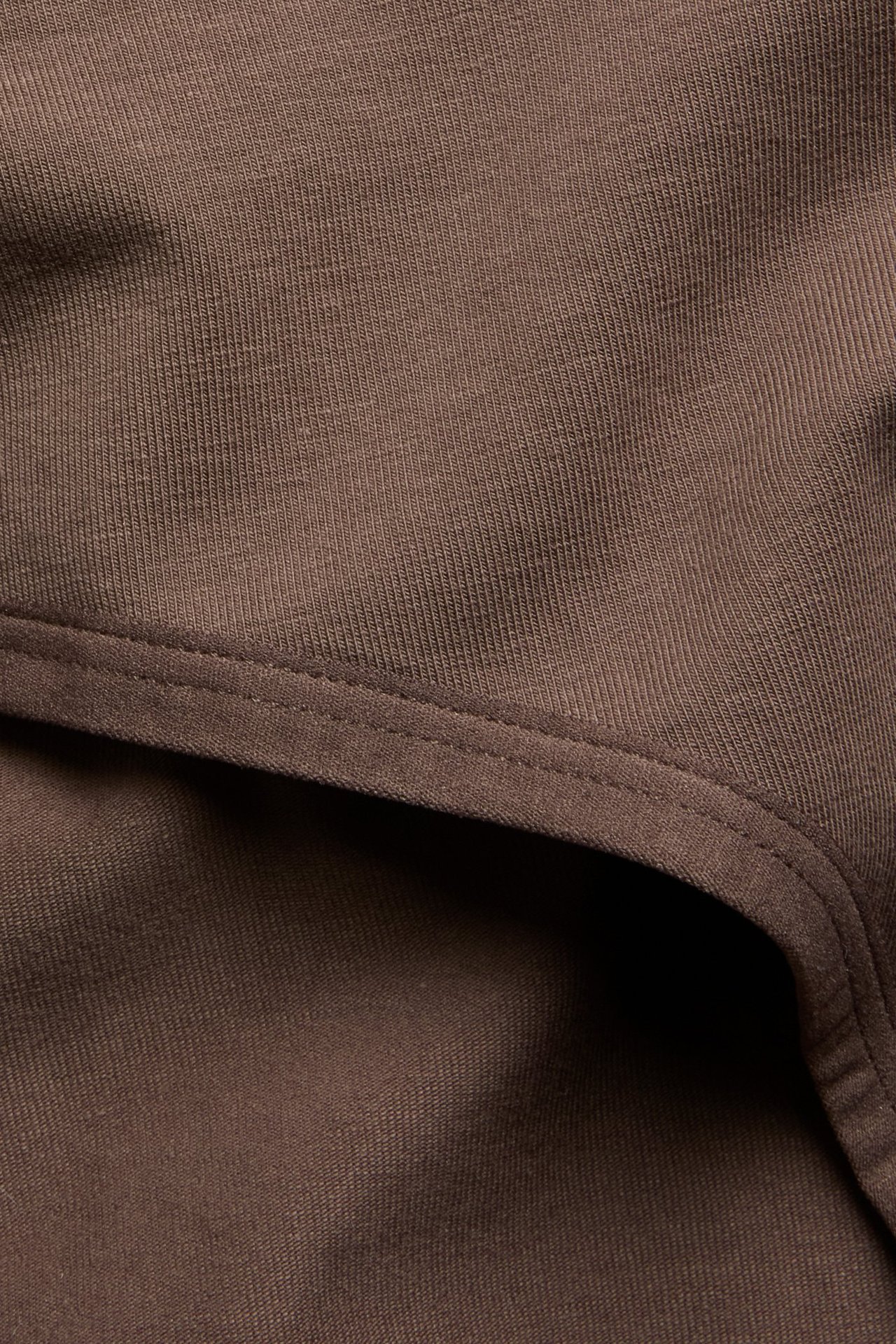 Zbliżenie ciemnobrązowych, jednolitych bawełnianych fig typu hipster z szerokim pasem.