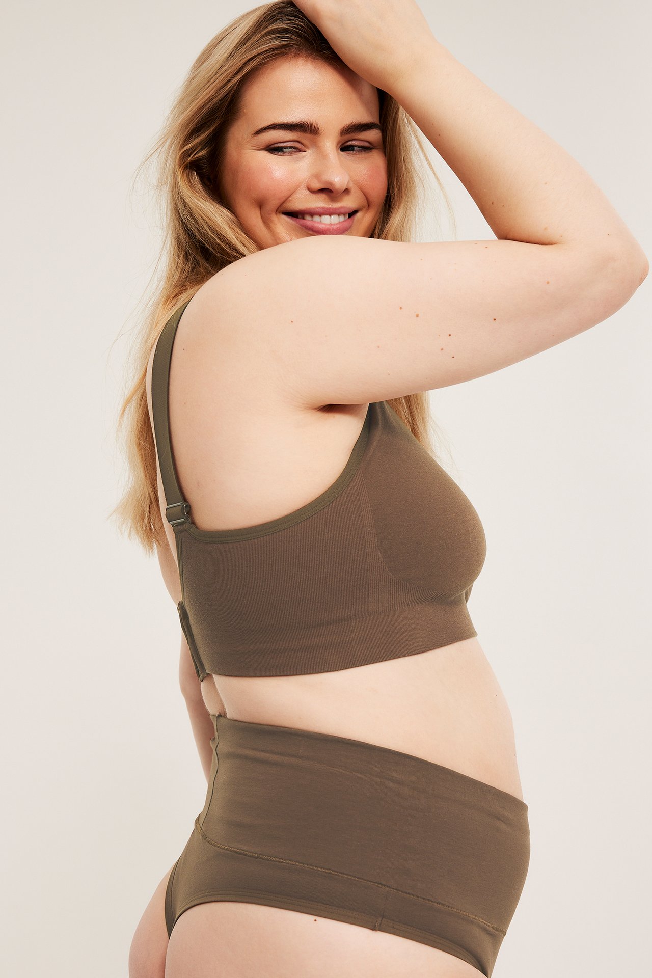 Sidevisning av en kvinne i mørk brun bomullsstringtruse med høy midje og matchende bralette.