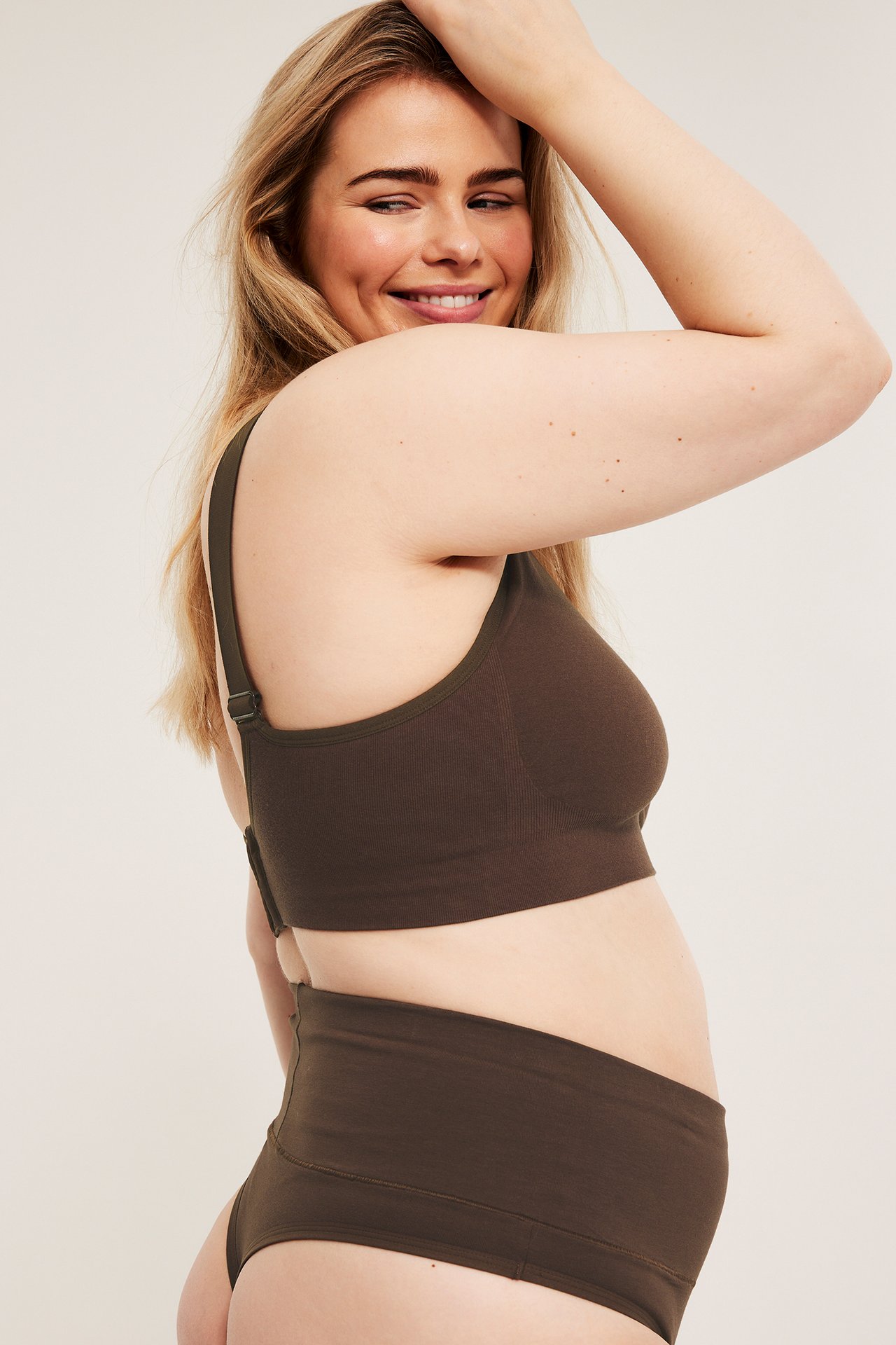 Sidebilde av kvinne i mørk brun bomullstringtruse med bred linning og matchende myk BH.