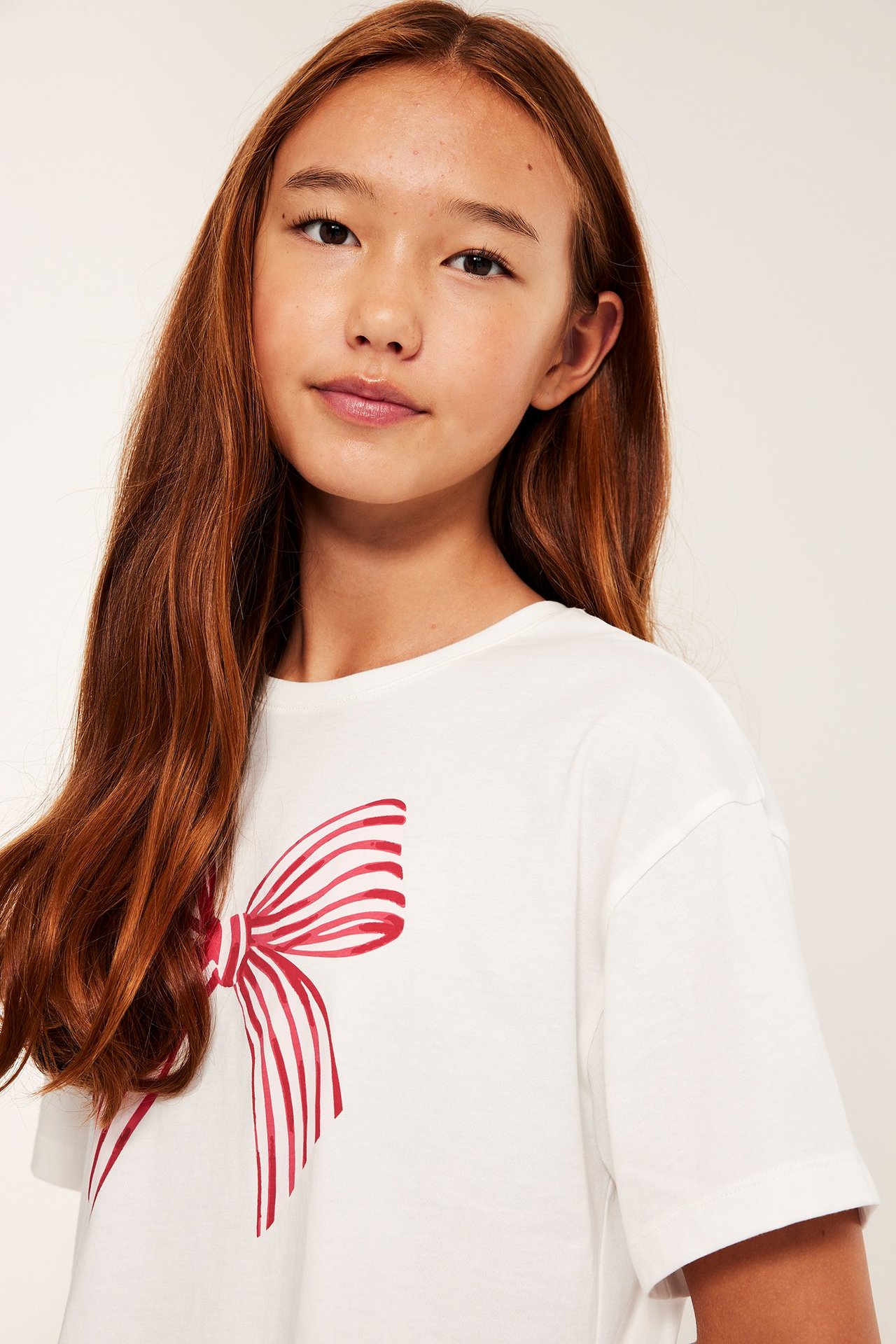 Tyttö offwhite pyjamissa, rusetti-kuosi ja shorts, etupuolelta.