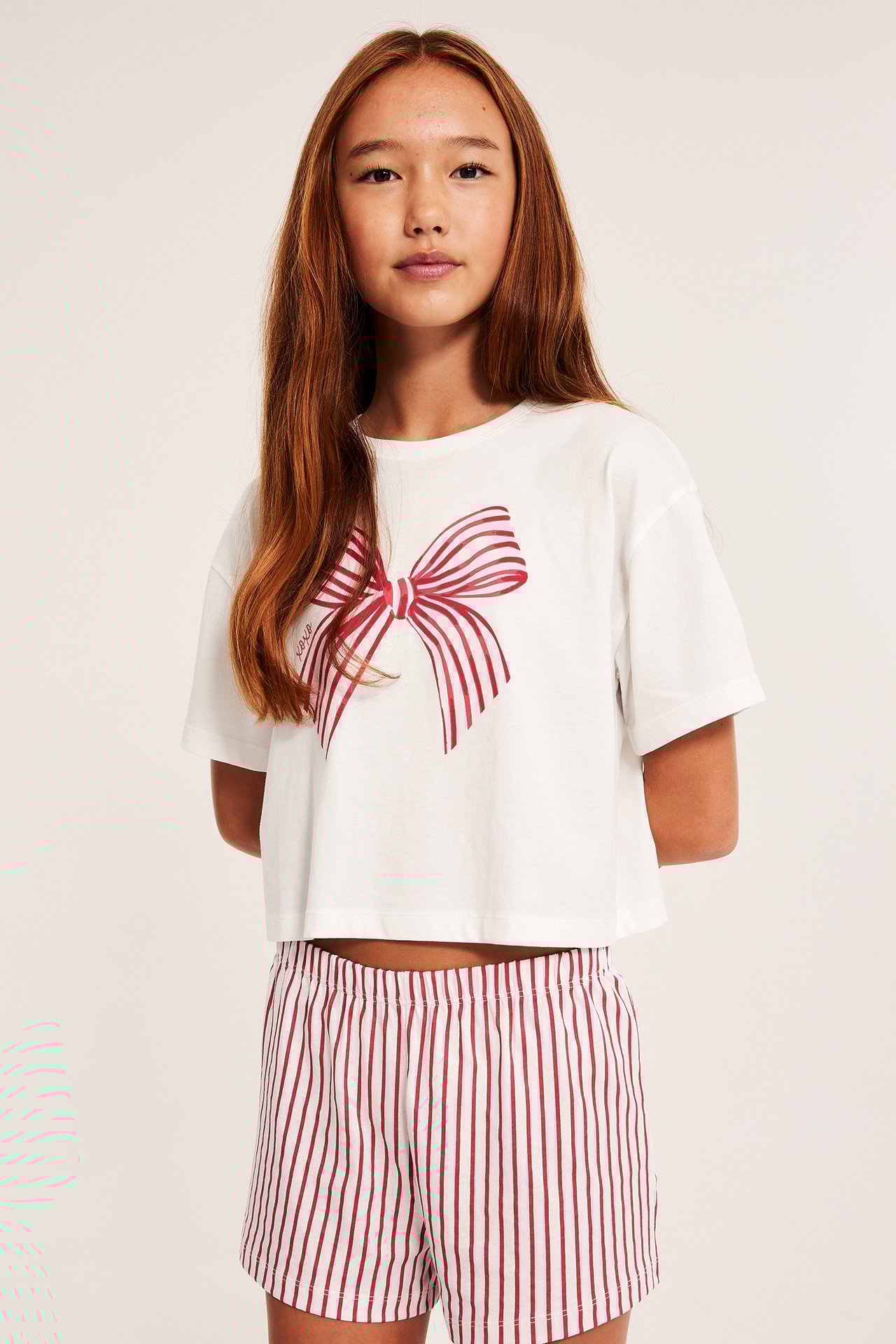 Offwhite lyhythihaisessa pyjamassa etupyhe ja raidalliset shortsit.