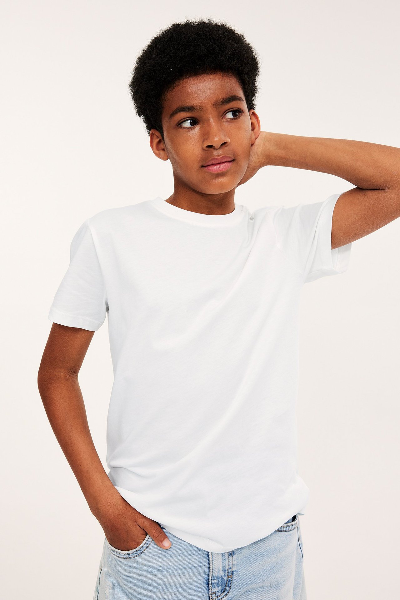 Edestäpäin: lapsi valkoisessa yksivärisessä puuvilla-t-paidassa ja vaaleansinisissä farkuissa.