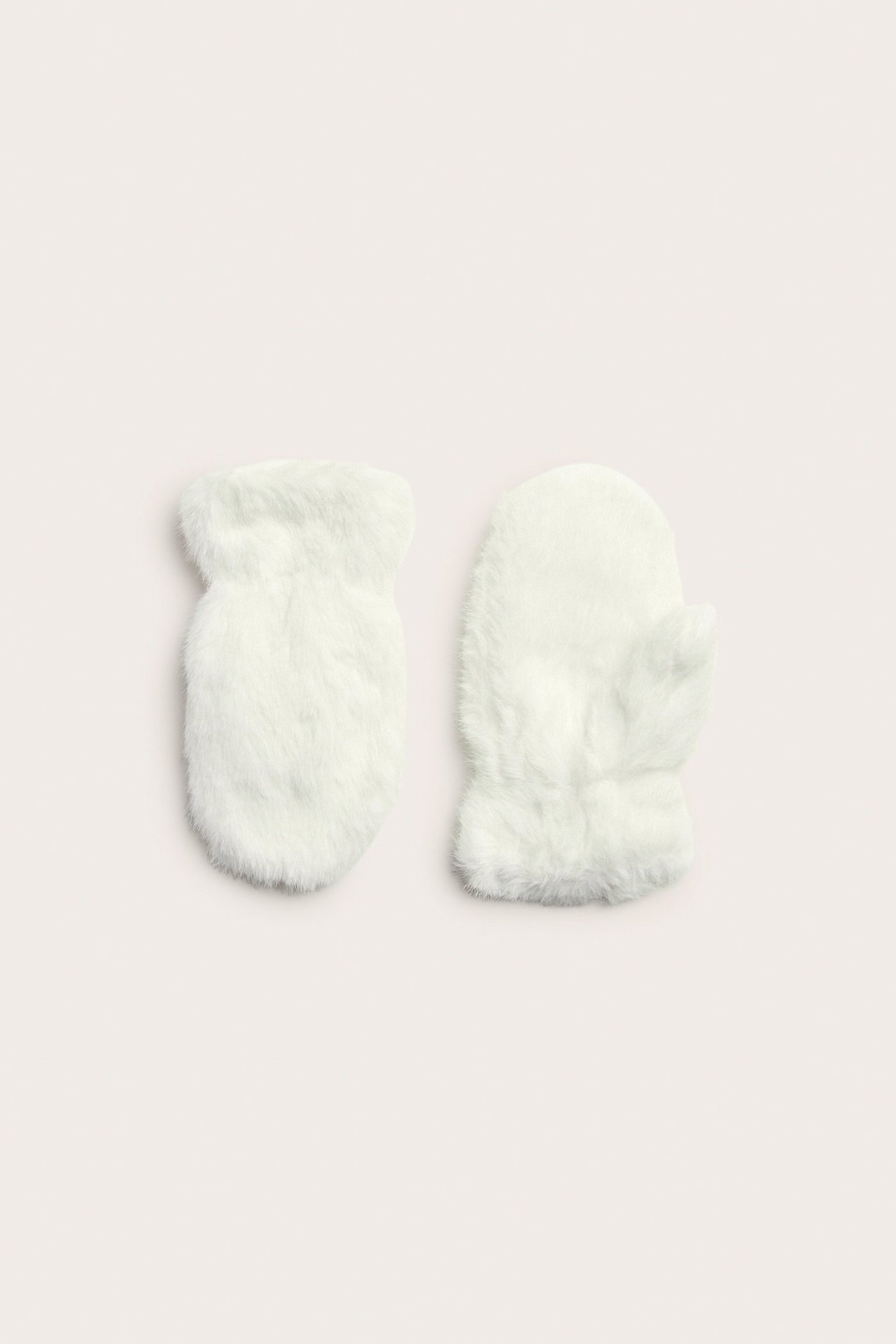 Widok z góry na parę kremowych, futrzanych rękawiczek z włochatą teksturą.