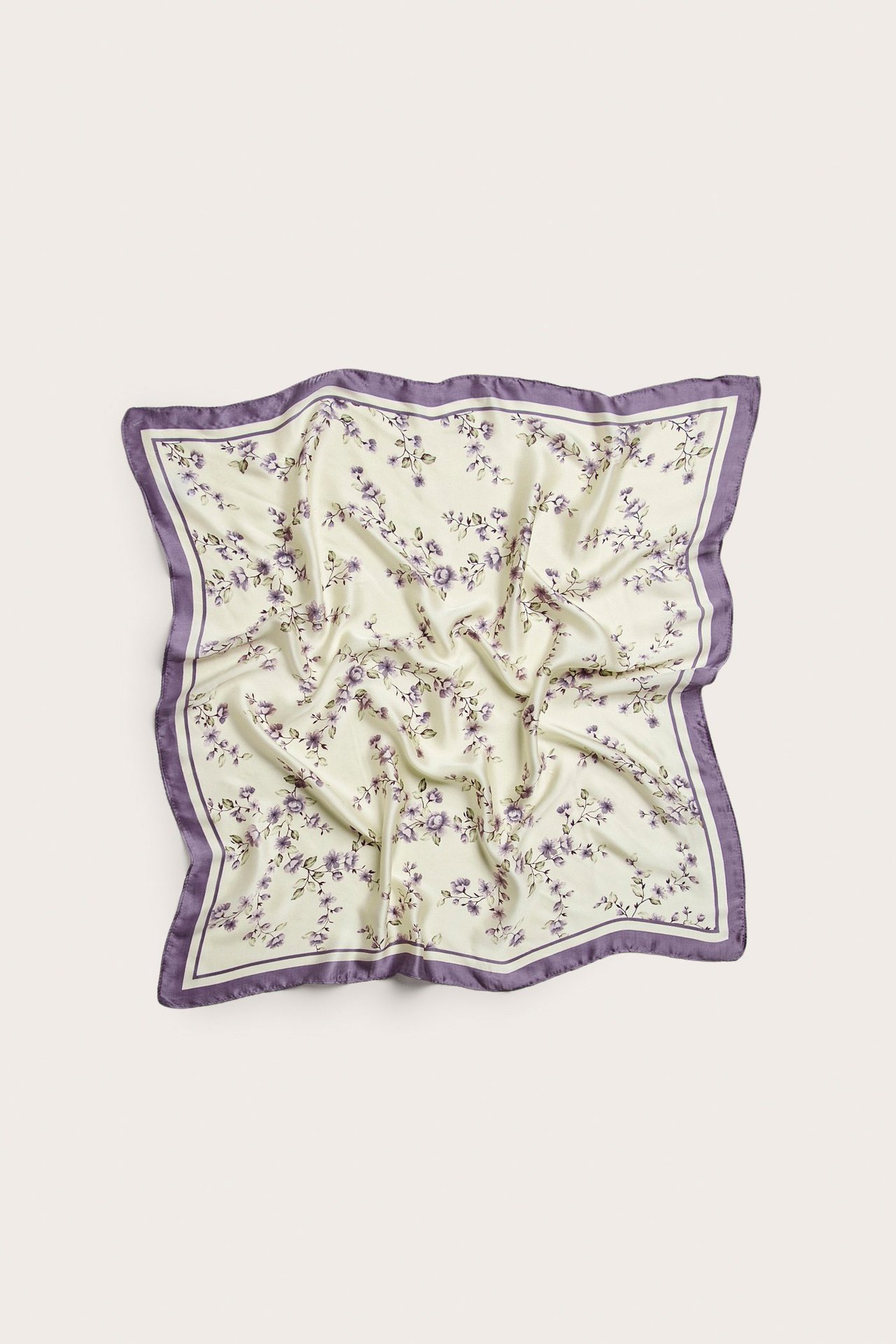 Ylhäältä: neliönmuotoinen vaaleanbeige polyesterihuivi, jossa violetti kukkakuvio ja violetti reuna.