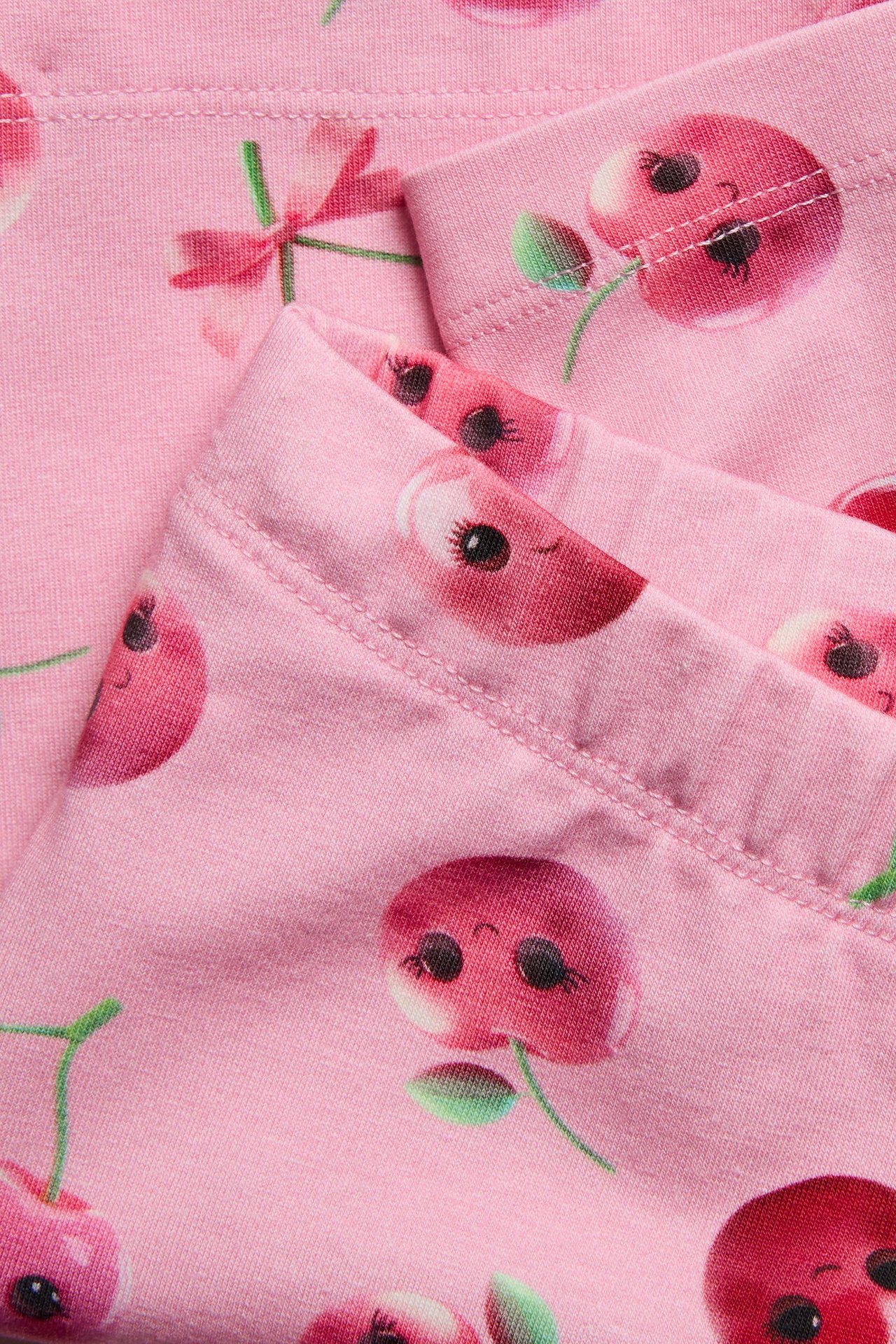 Zbliżenie różowych szortów kolarskich dziecięcych z uroczym wzorem wiśni.