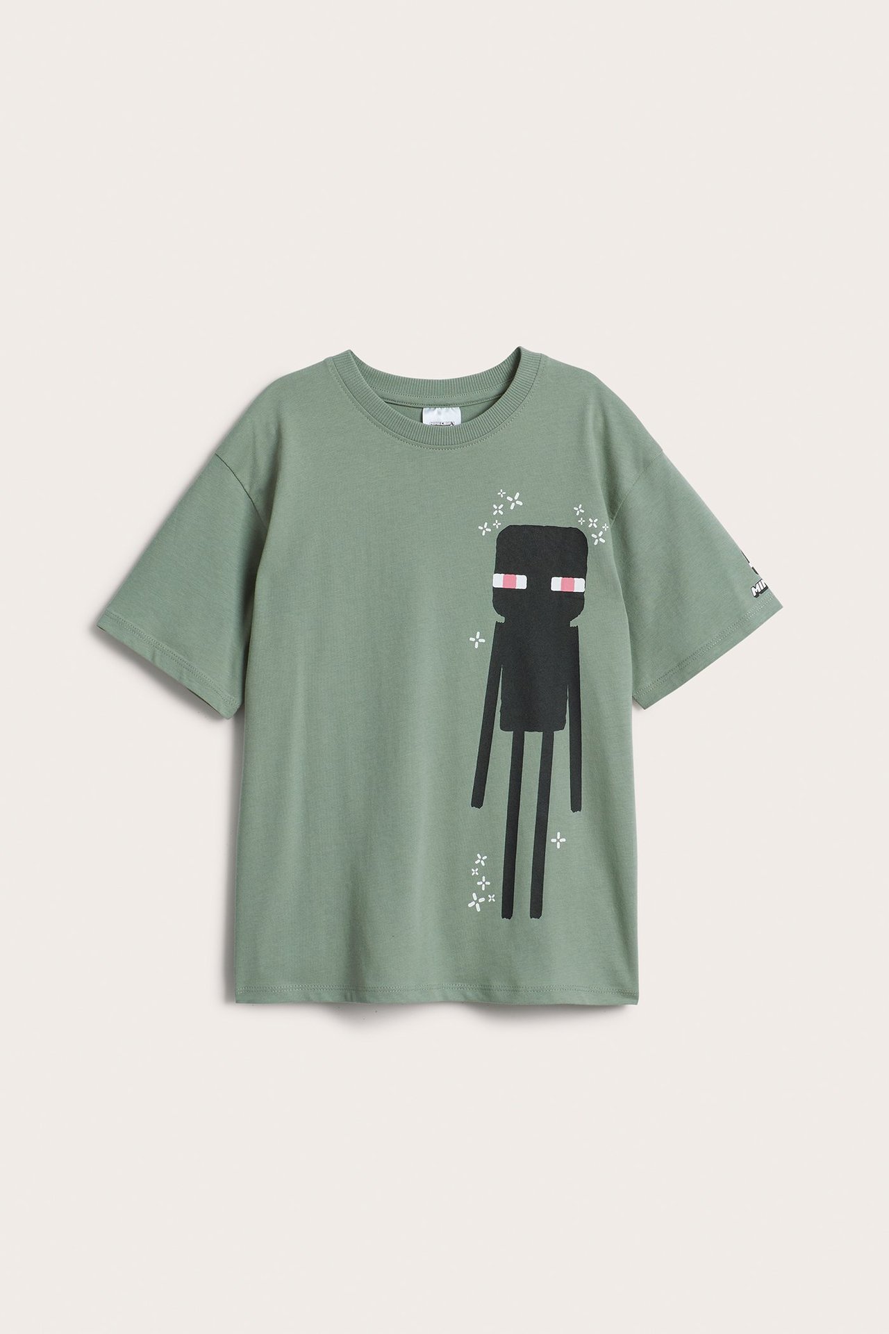 Framifrån: Grön t-shirt i bomull för barn med stort svart Minecraft Enderman-tryck framtill.