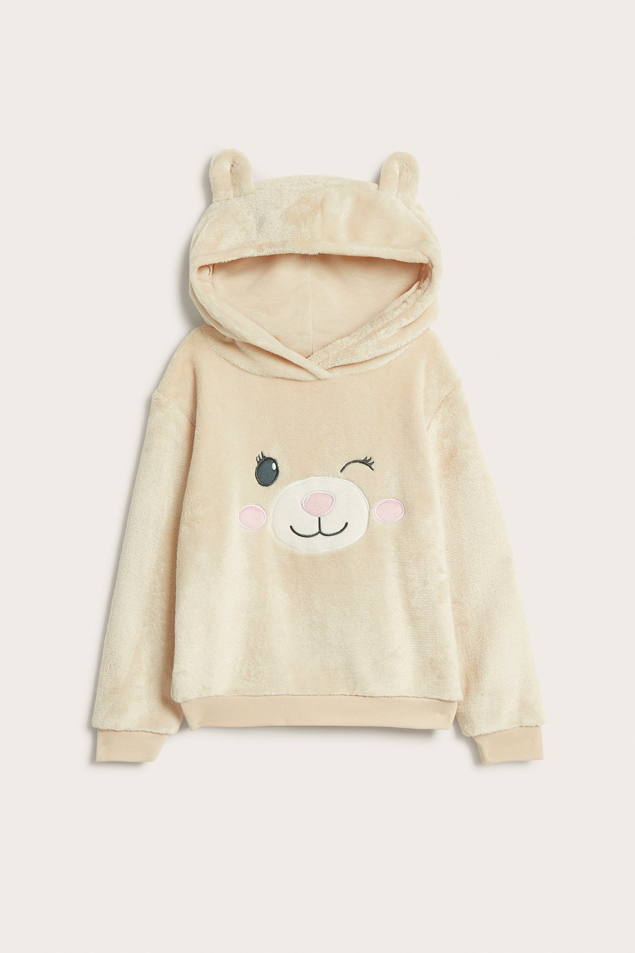 Edestä: Lasten vaaleanbeige pörröinen huppari korvilla ja brodeeratulla silmää iskevällä karhun kasvoilla.