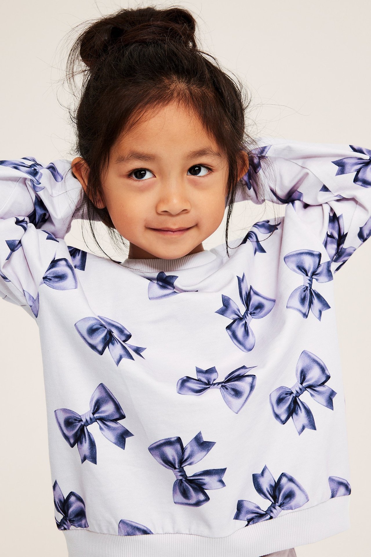 Lapsityttö, joka käyttää valkoista, kuviollista pitkähihaista toppia, röyhelökuvio, puuvillaa.