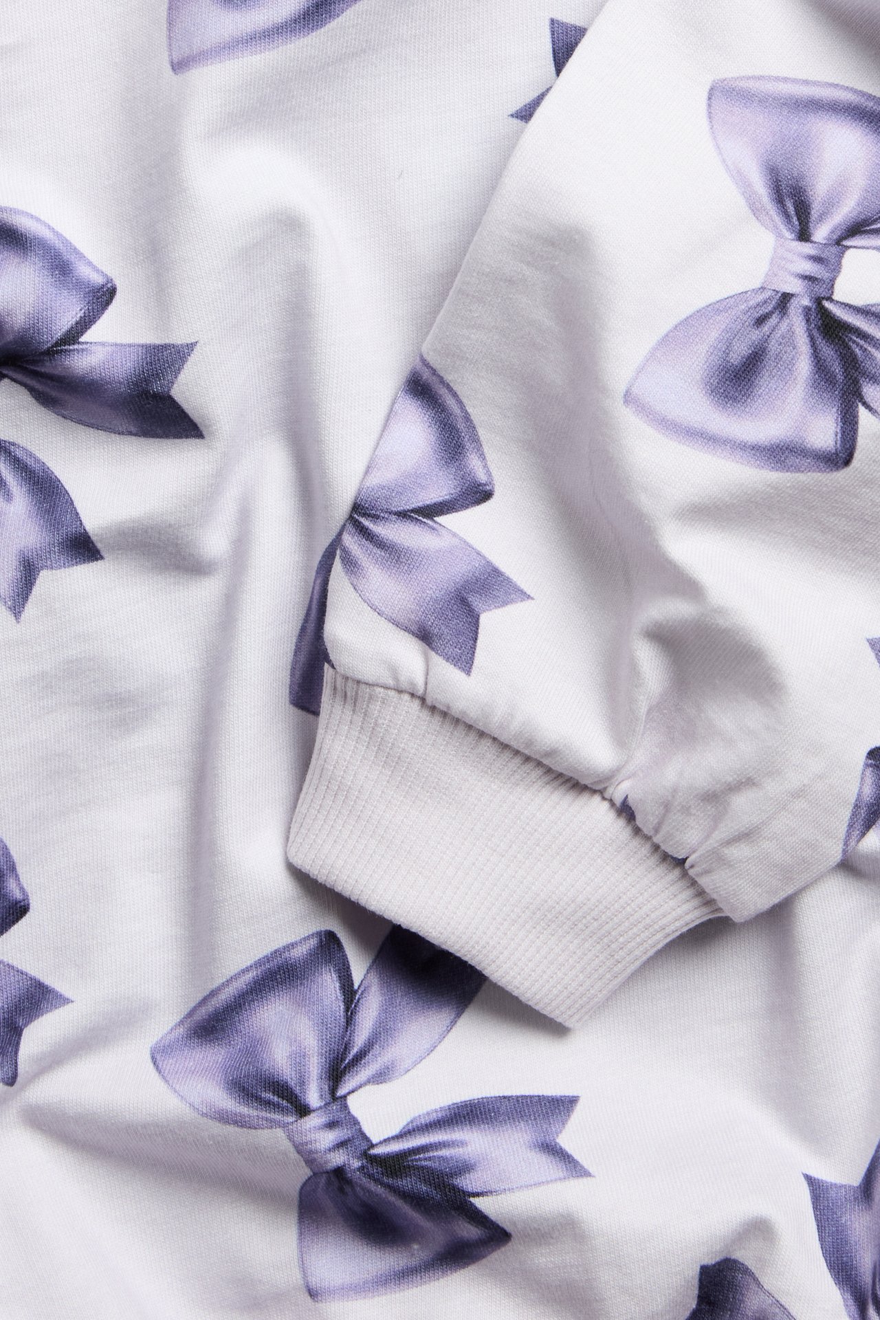 Pitkähihaista valkoista puuvillapaitaa, rusetti-kuvio ja ribbesteippaus.