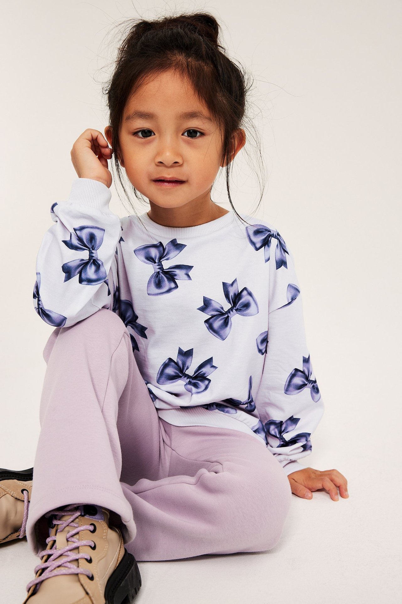 Långärmad topp i vit bomull med blå rosett-mönster, raglanärm, ribbad hals, ärmslut och nederkant.