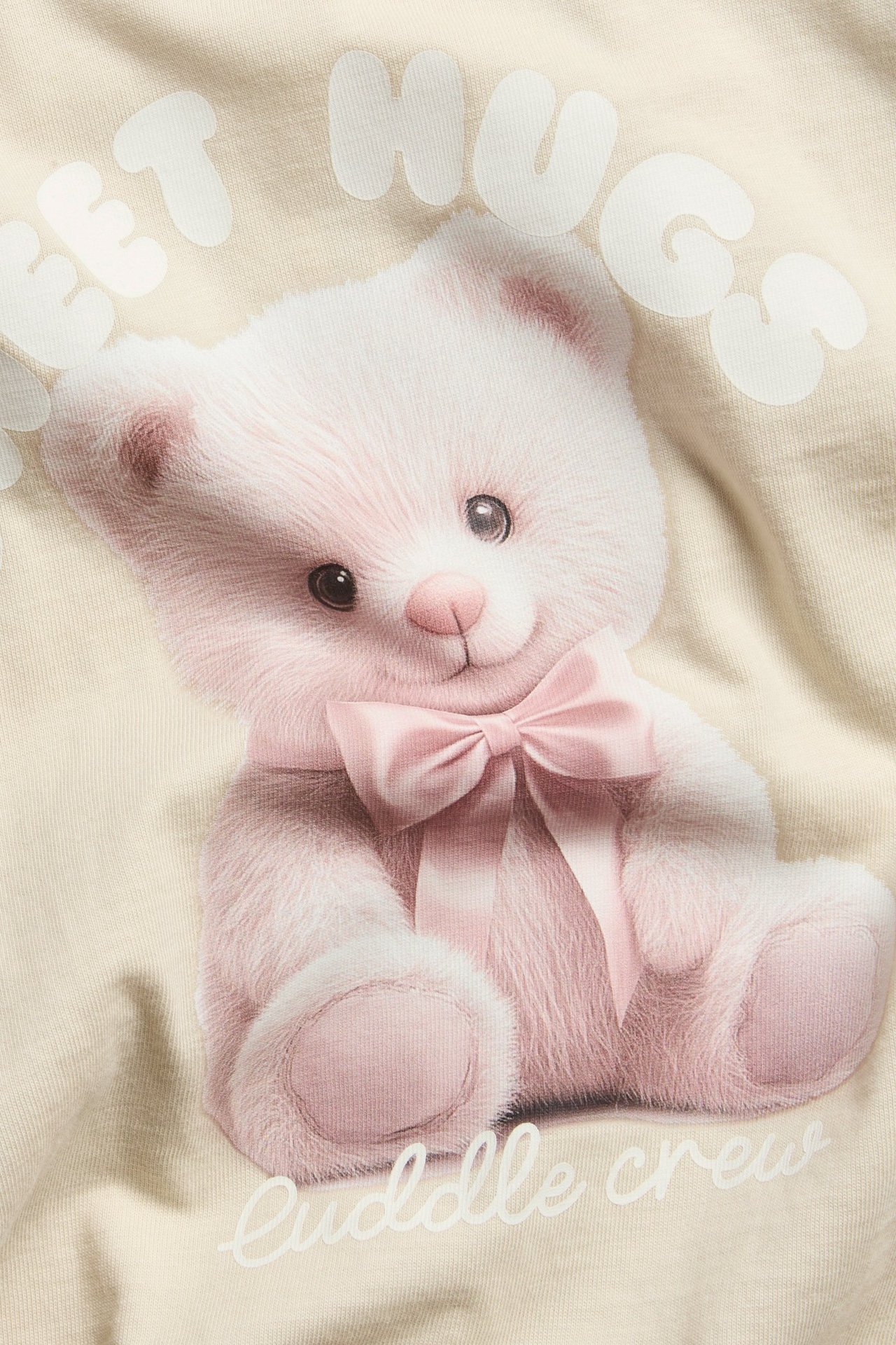 Pitkähihaiset vaaleanbeige toppi, etualla pinkki marja-aronen kuva ja teksti.