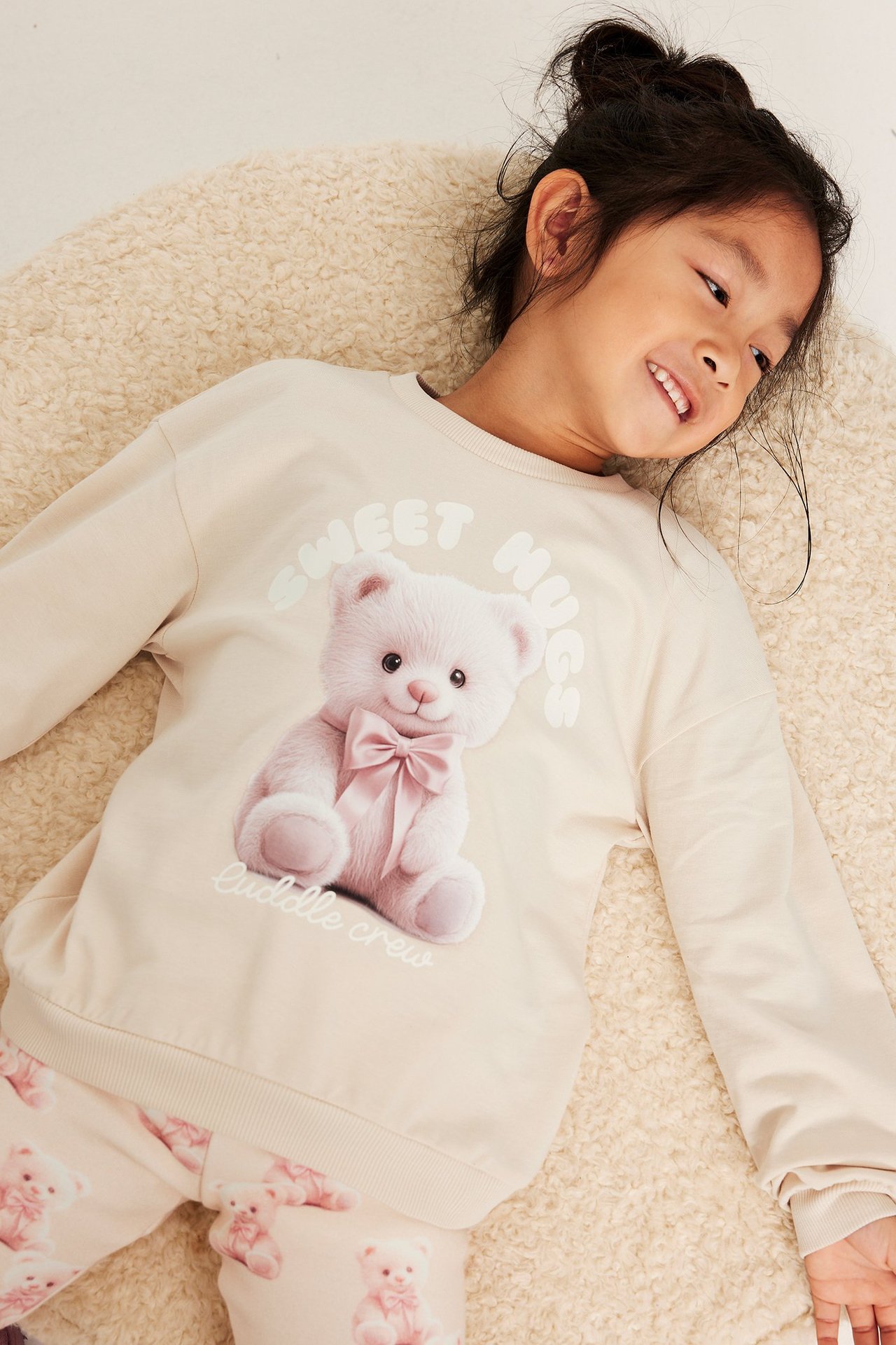 Långärmad beige topp med tryck av ett nallebjörn och text, på ett barn.