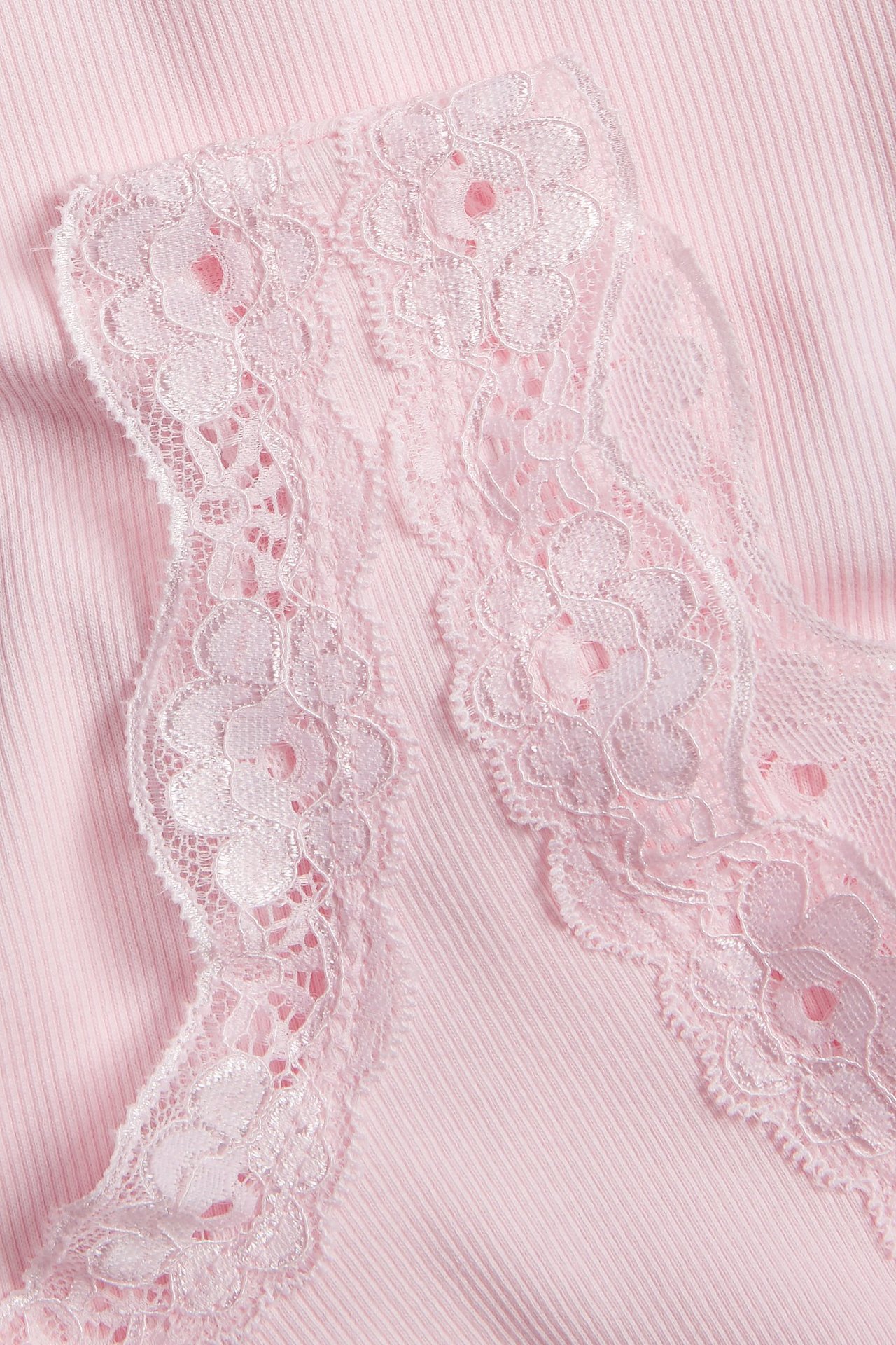 Zbliżenie różowego prążkowanego topu z delikatną koronkową lamówką w kwiaty wzdłuż dekoltu.