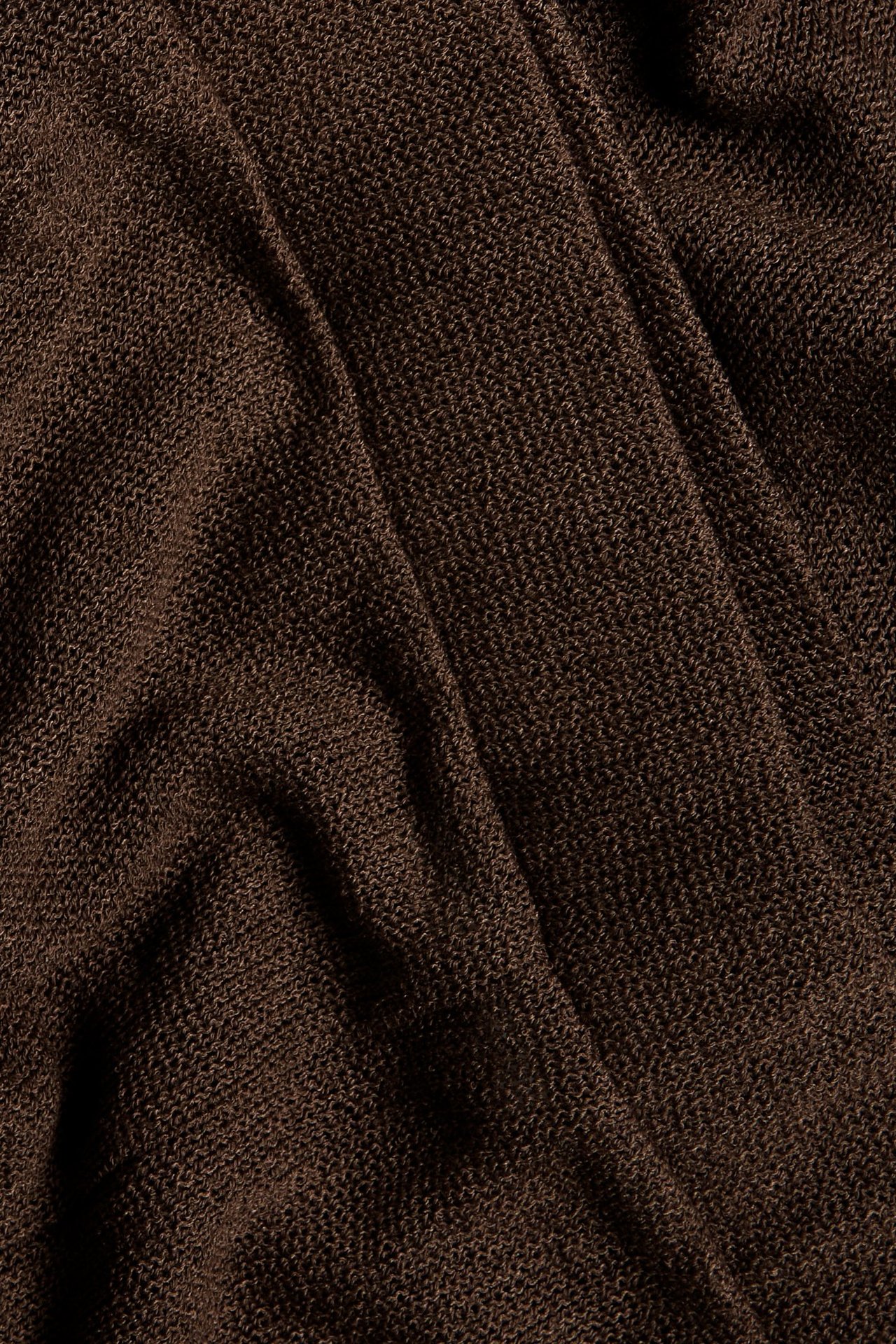 Zbliżenie na ciemnobrązowy, strukturalny materiał dżersejowy o wyglądzie suchego lnu.