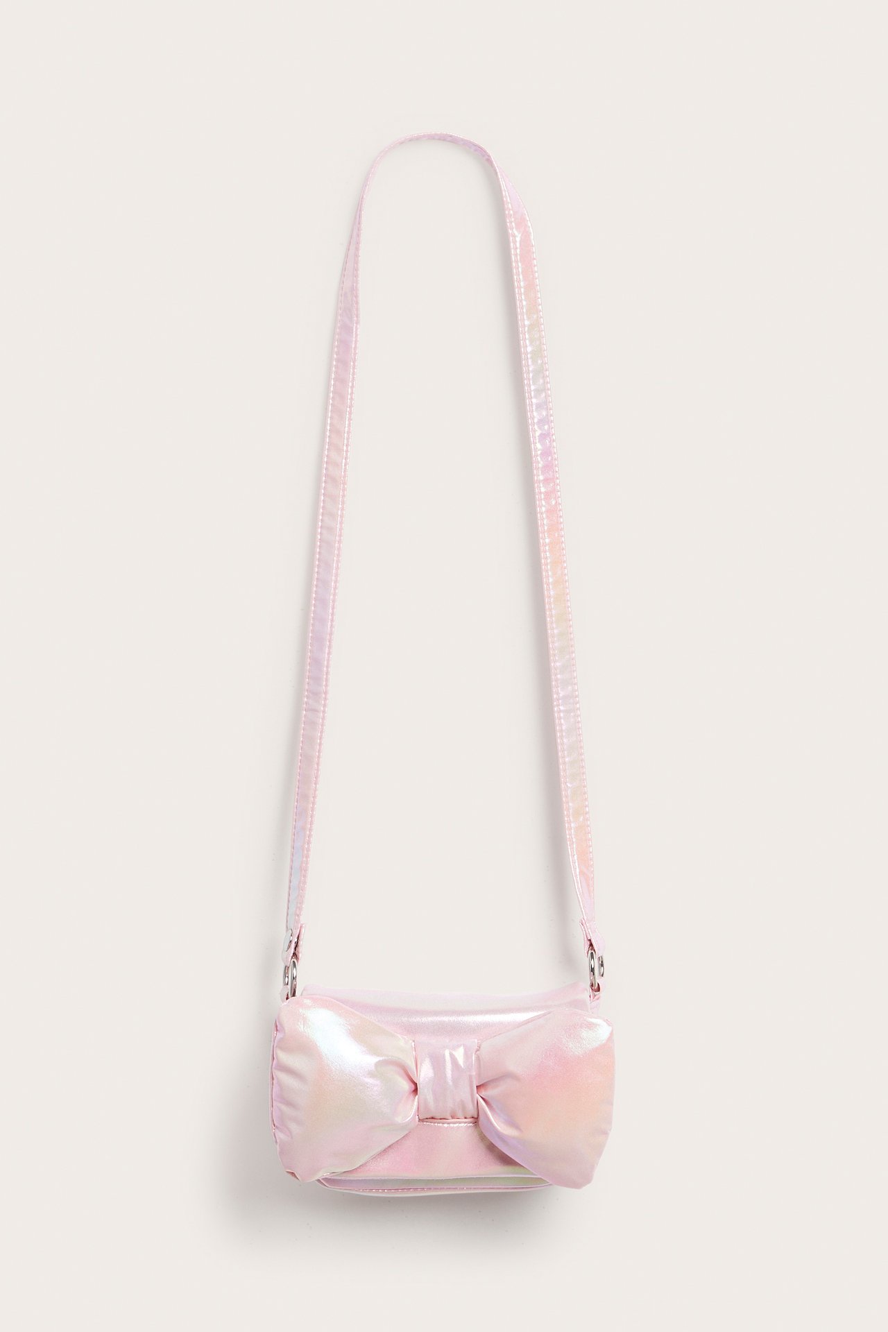 Edestäpäin vaaleanpunainen, hohtava olkalaukku isolla rusetilla.