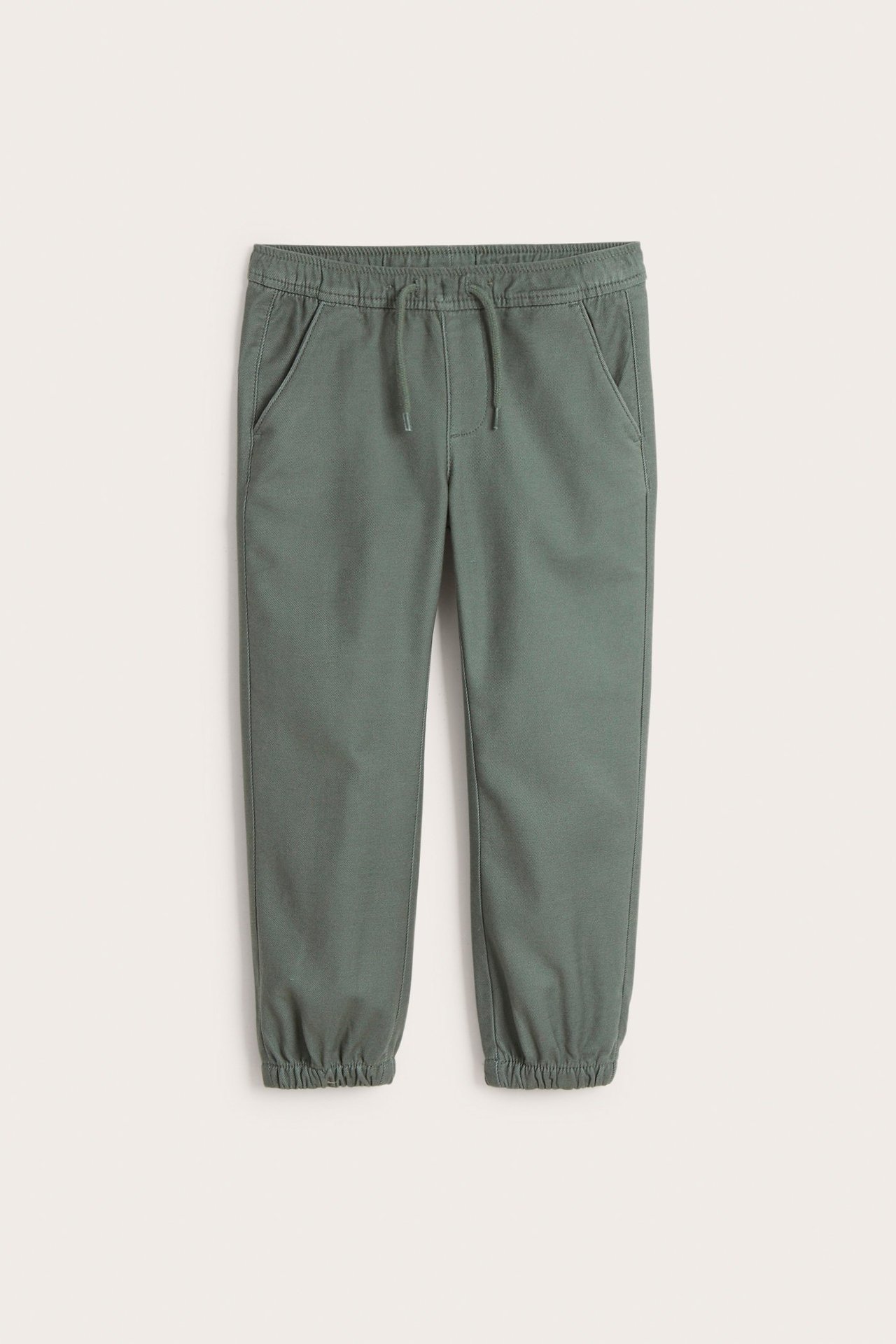 Edestä: tummanvihreät lasten stretch-chinot, joissa kiristysnyörillinen vyötärö, etutaskut ja joustavat lahkeensuut.