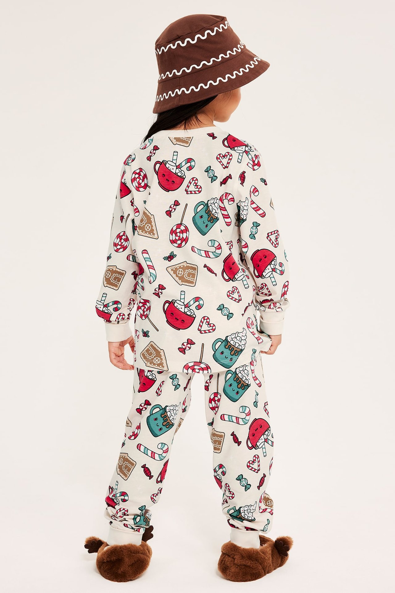 Barnpyjamas med julinspirerat tryck i ljusbeige, med mudd i benen och ärmslut.