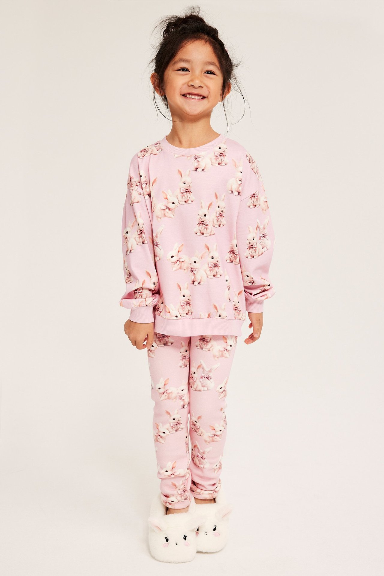 Onnellinen tyttö vaaleanpunaisissa pupumallissakin, lämpimissä legginsseissä ja pehmeissä pupunkengissä.