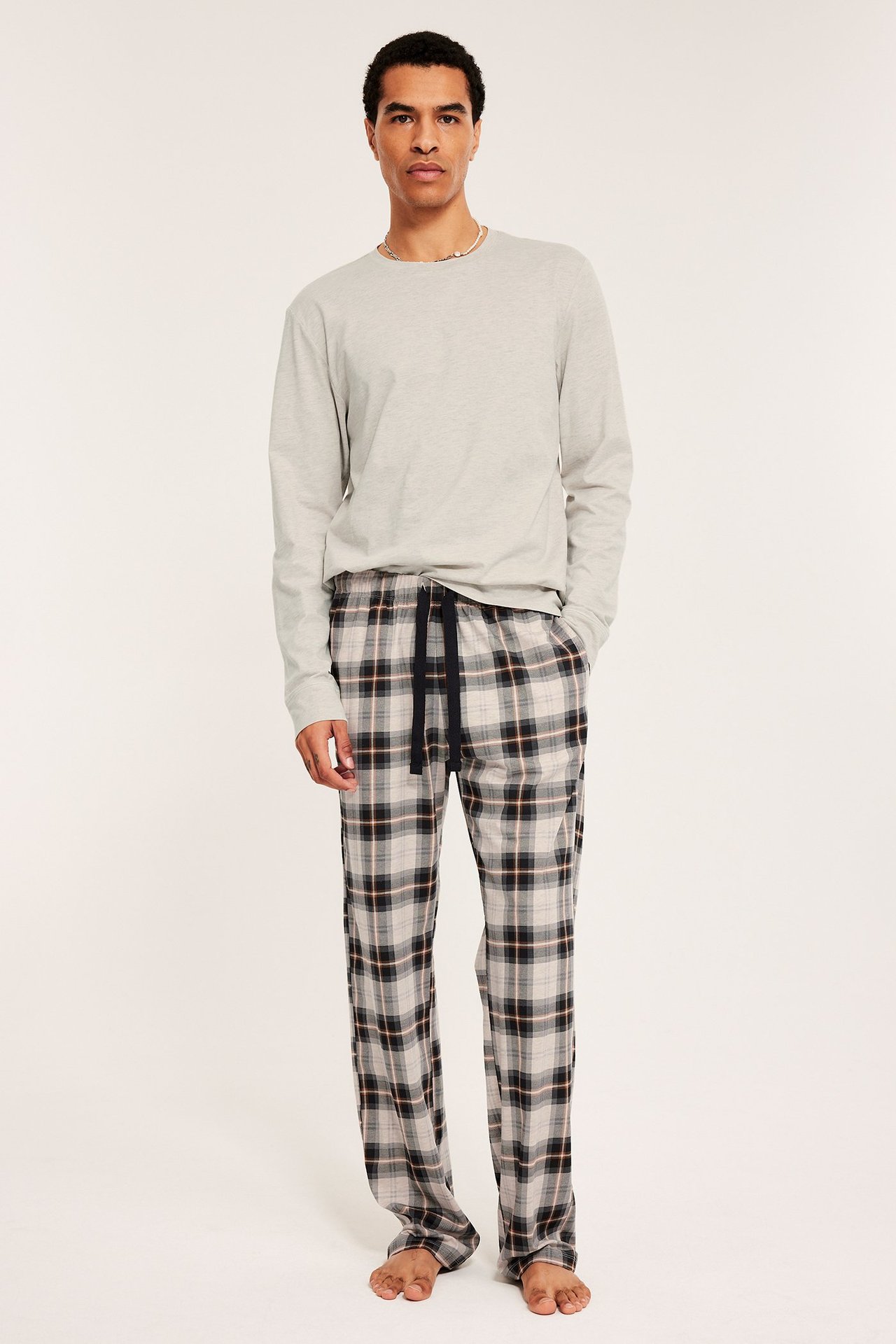 Mies beige-melange-pyjamat, pitkähihaiset ja ruudulliset housut, taskut.