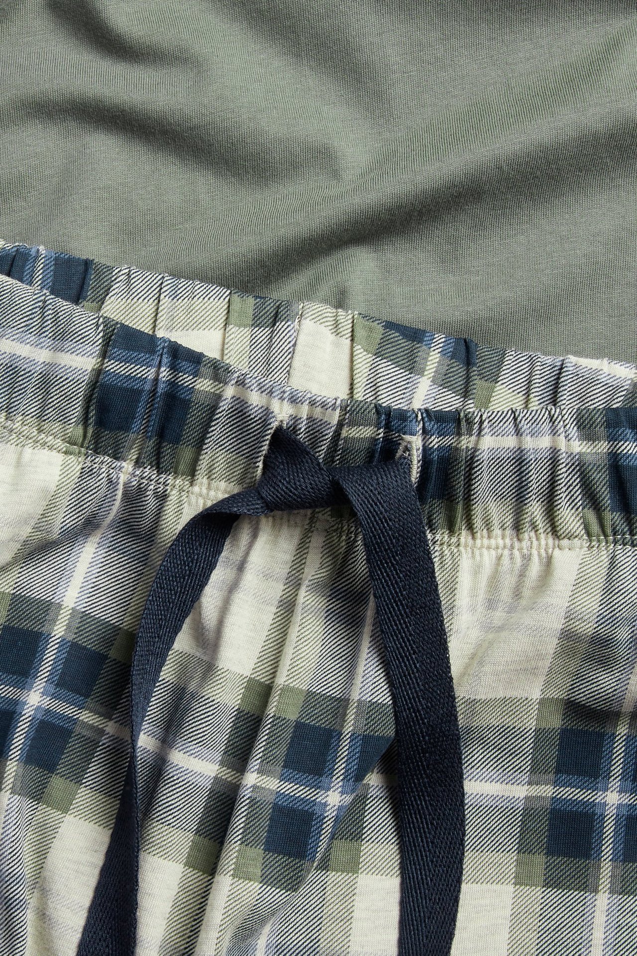 Męskie zielono-niebiesko-białe bawełniane spodnie piżamowe w kratę ze sznurkiem, z zielonym topem.