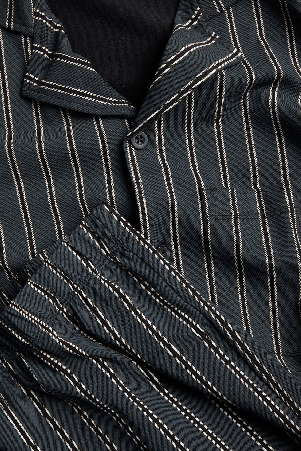 Zbliżenie męskiej ciemnoszarej piżamy w paski z trykotu, z zapinaną górą i spodniami z gumką.