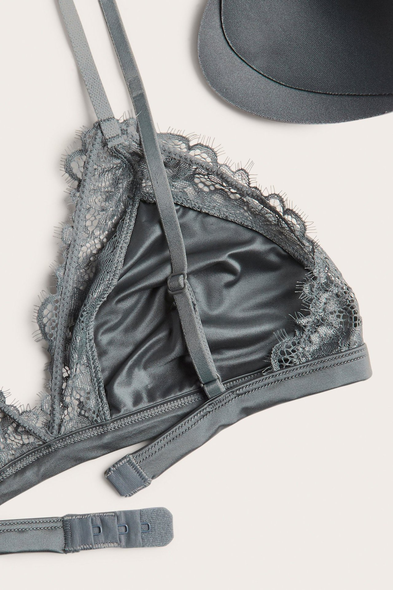 Zbliżenie na ciemnoszary biustonosz bralette z koronkowymi krawędziami, regulowanymi ramiączkami i oddzielną wkładką.