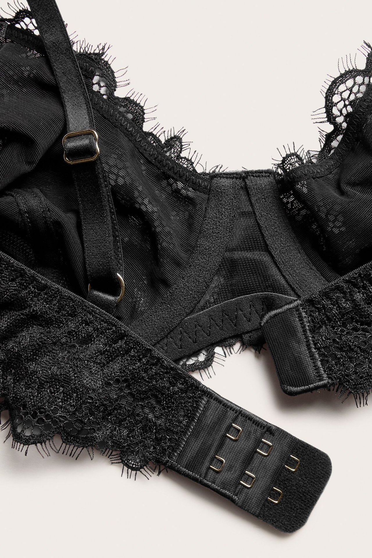 Nærbilde bakfra av en svart blonde-bh med justerbare stropper og hektelukking.