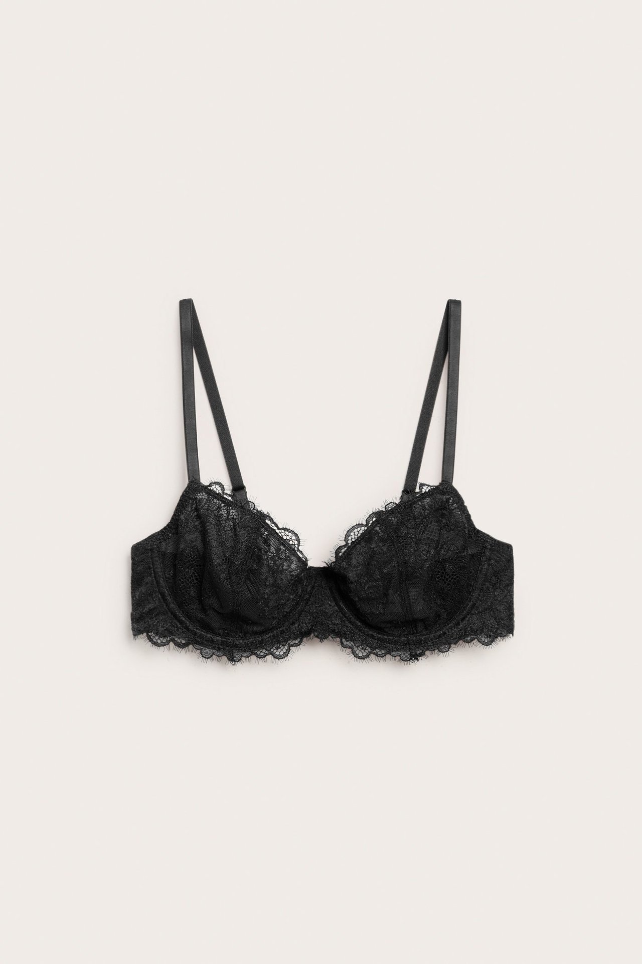 Frontbilde av en svart blonde-BH med spiler, smale stropper og bølgete kanter.