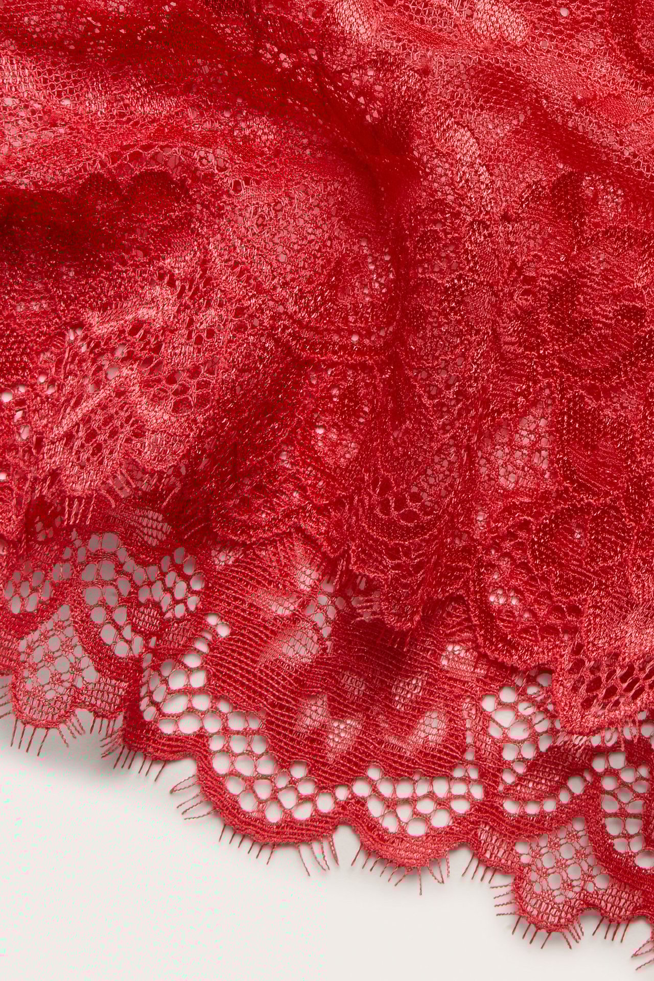 Zbliżenie czerwonych koronkowych majtek cheeky z falistym brzegiem.