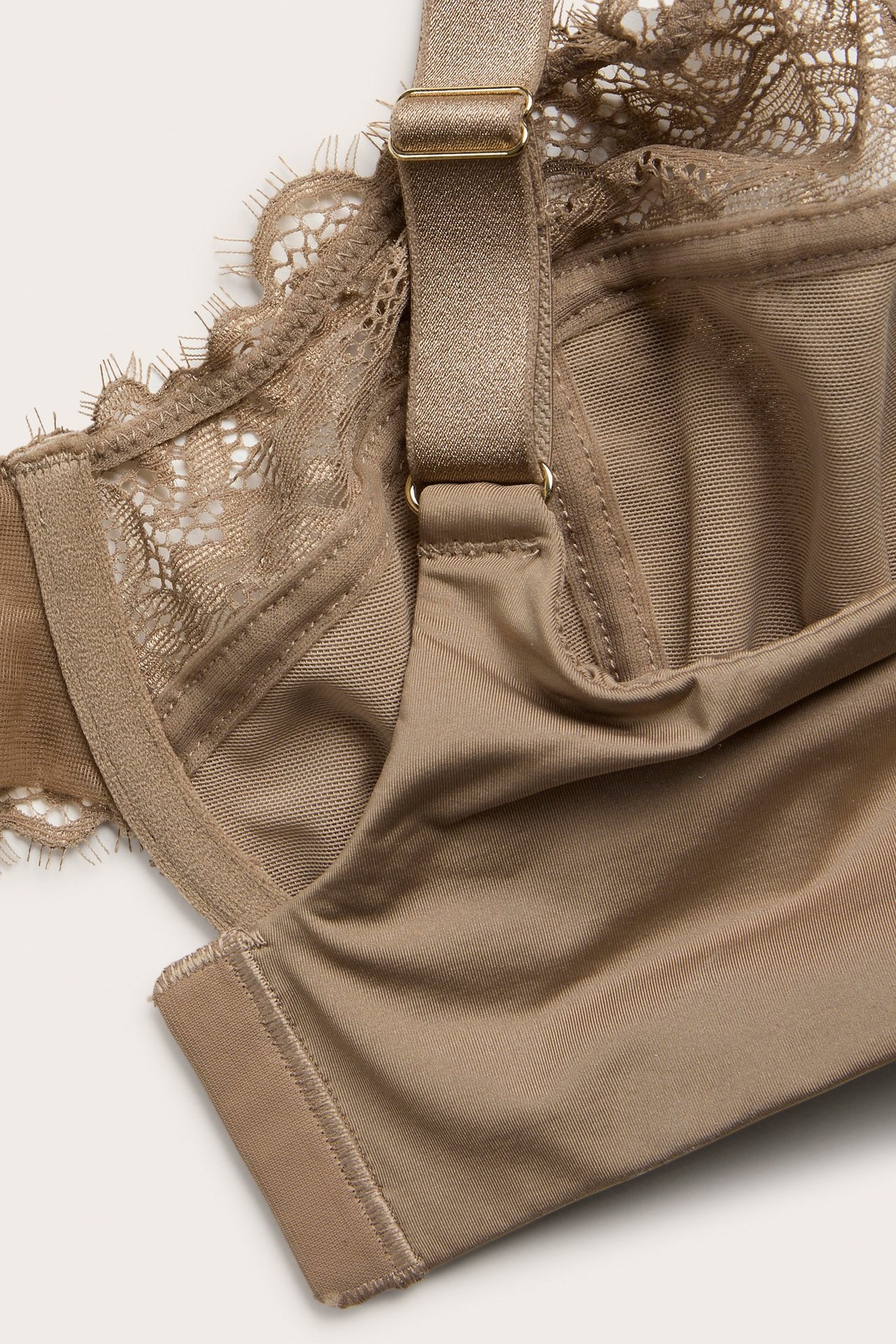 Nærbilde av en beige blonde-BH med bøyle, justerbar stropp og glatt cup.