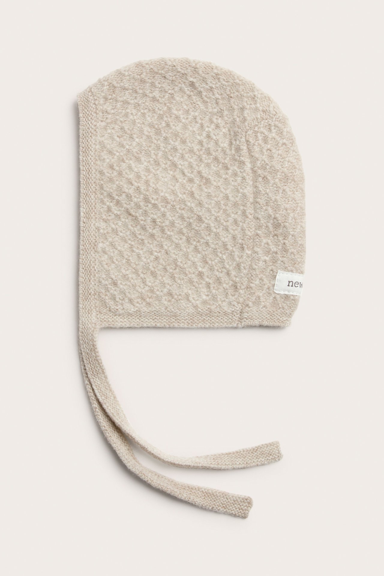 Flatt lagt lys beige teksturert strikket babykyse med knytebånd.