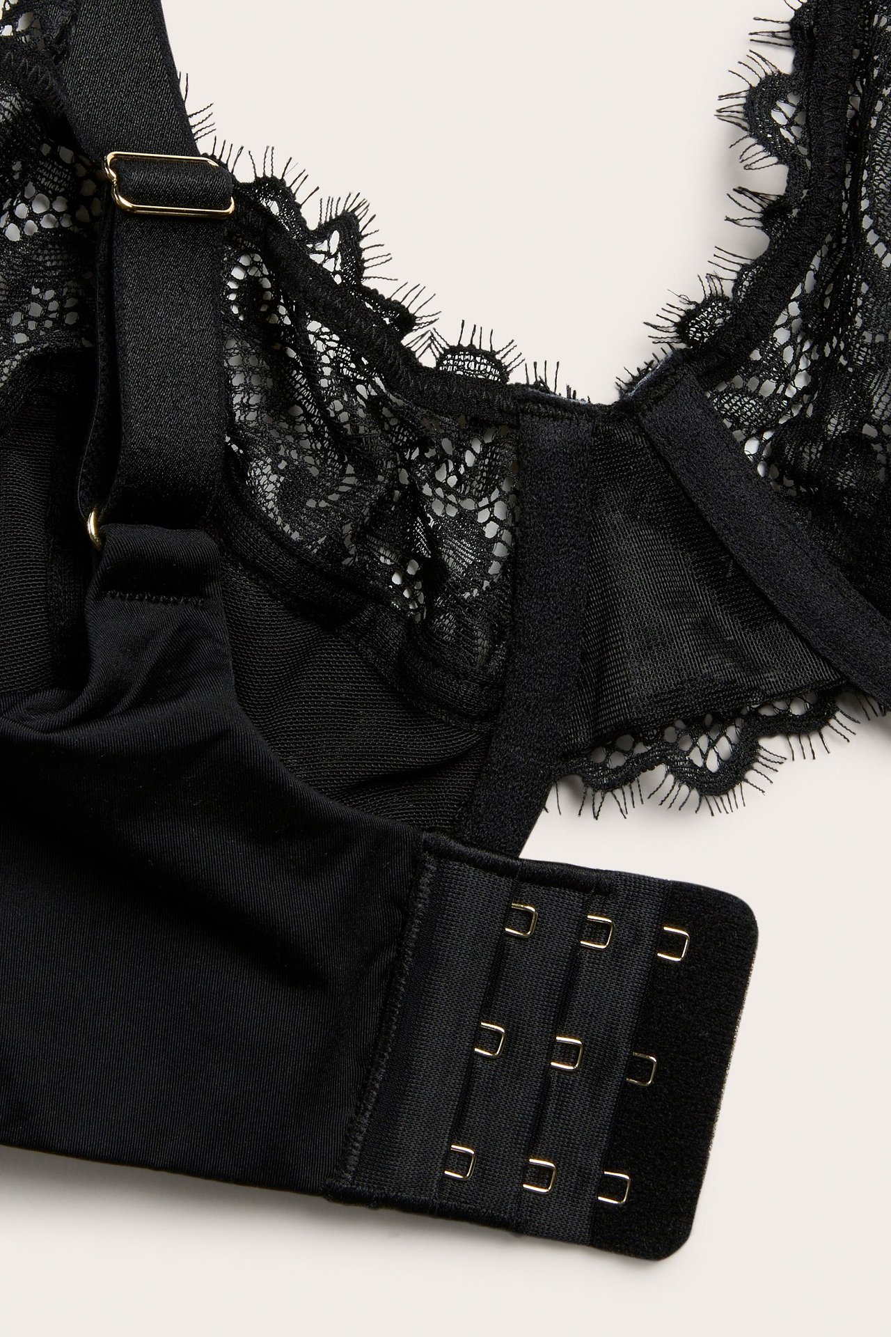 Nærbilde av en svart blonde-bh med bøyle, justerbare stropper og hektelukking.
