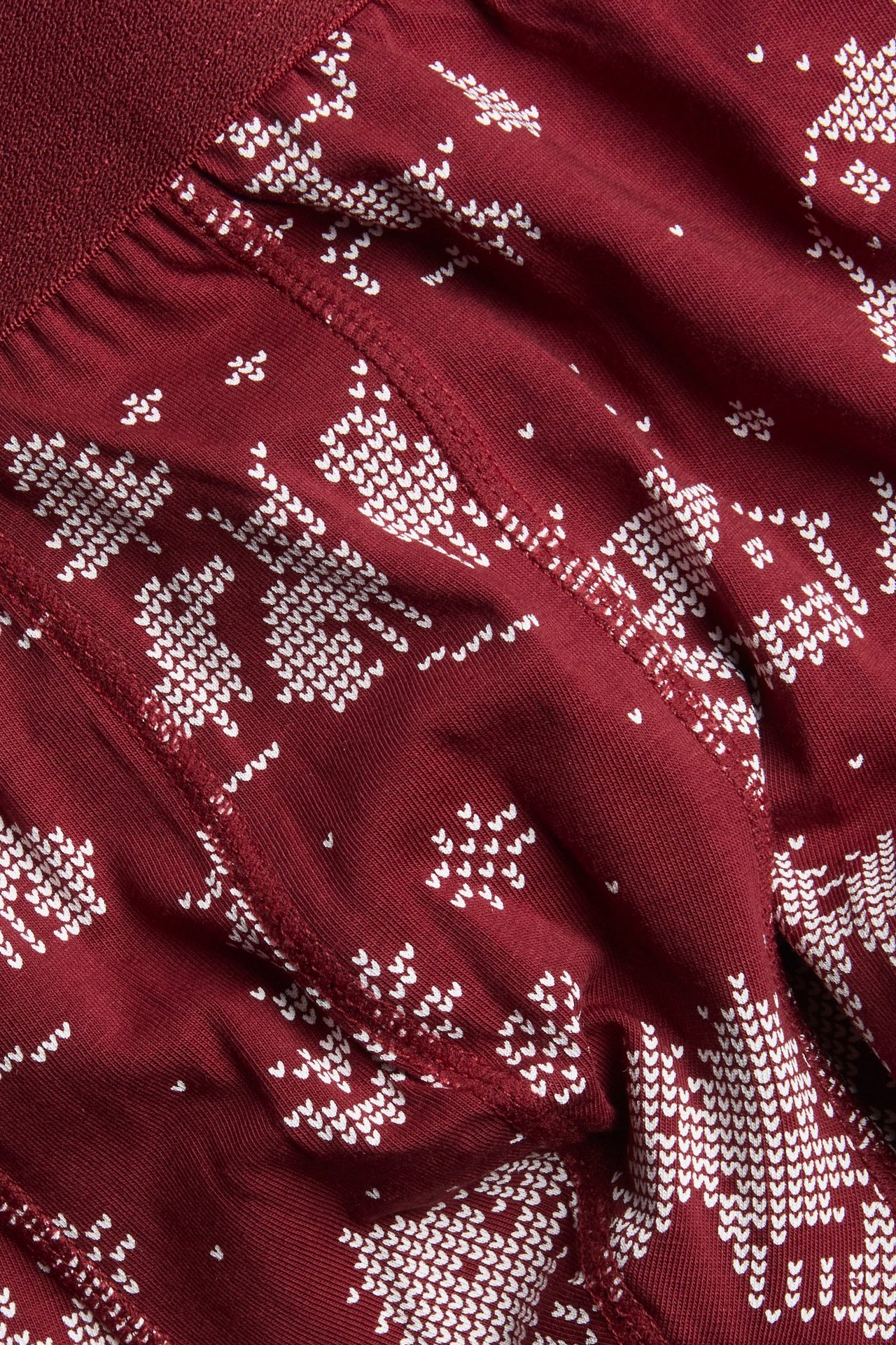 Nærbilde av røde mønstrede herreboxere med hvitt julemønster i bomull.