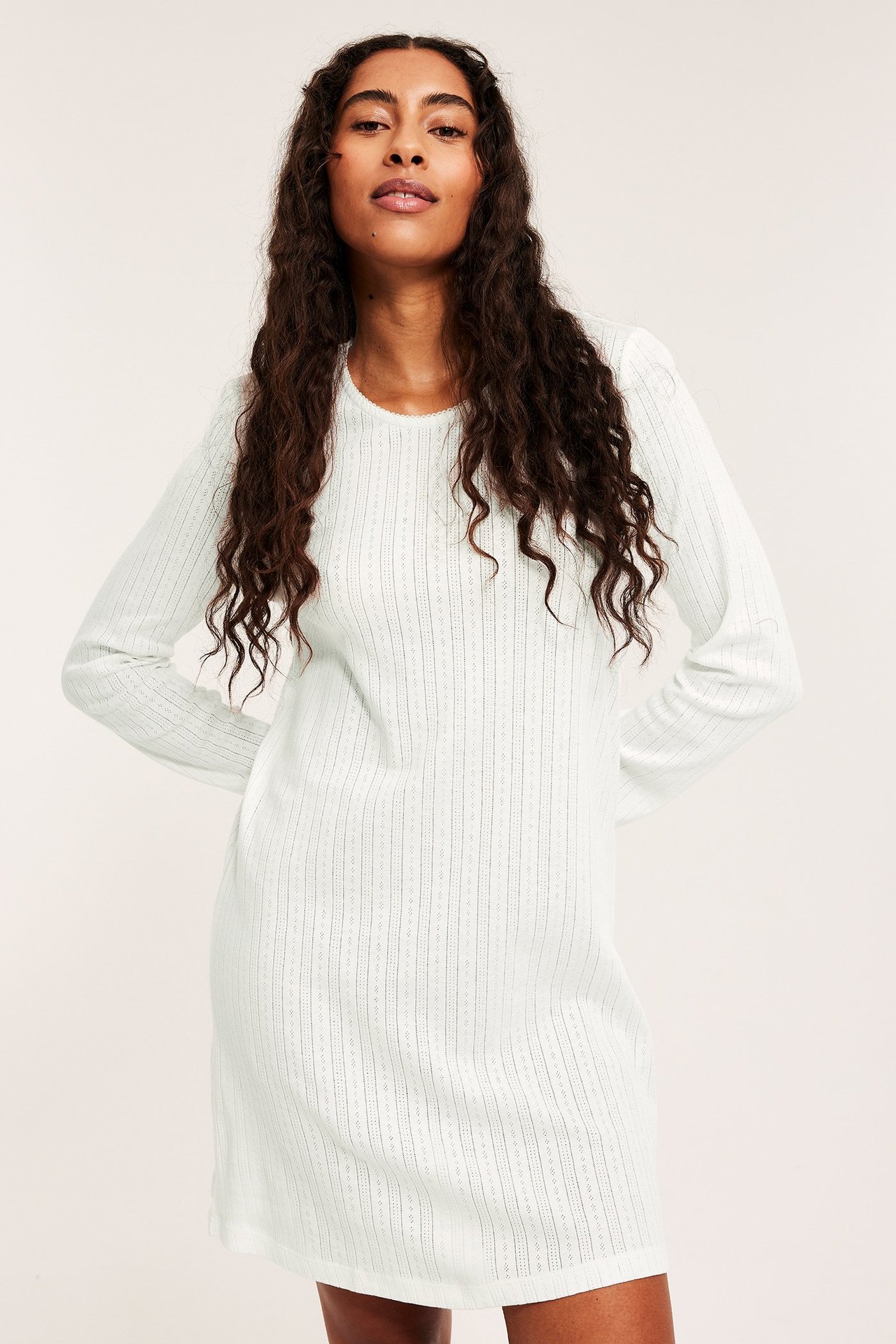 Modelka w białej nocnej sukni z długim rękawem, poitelle, do kolan.