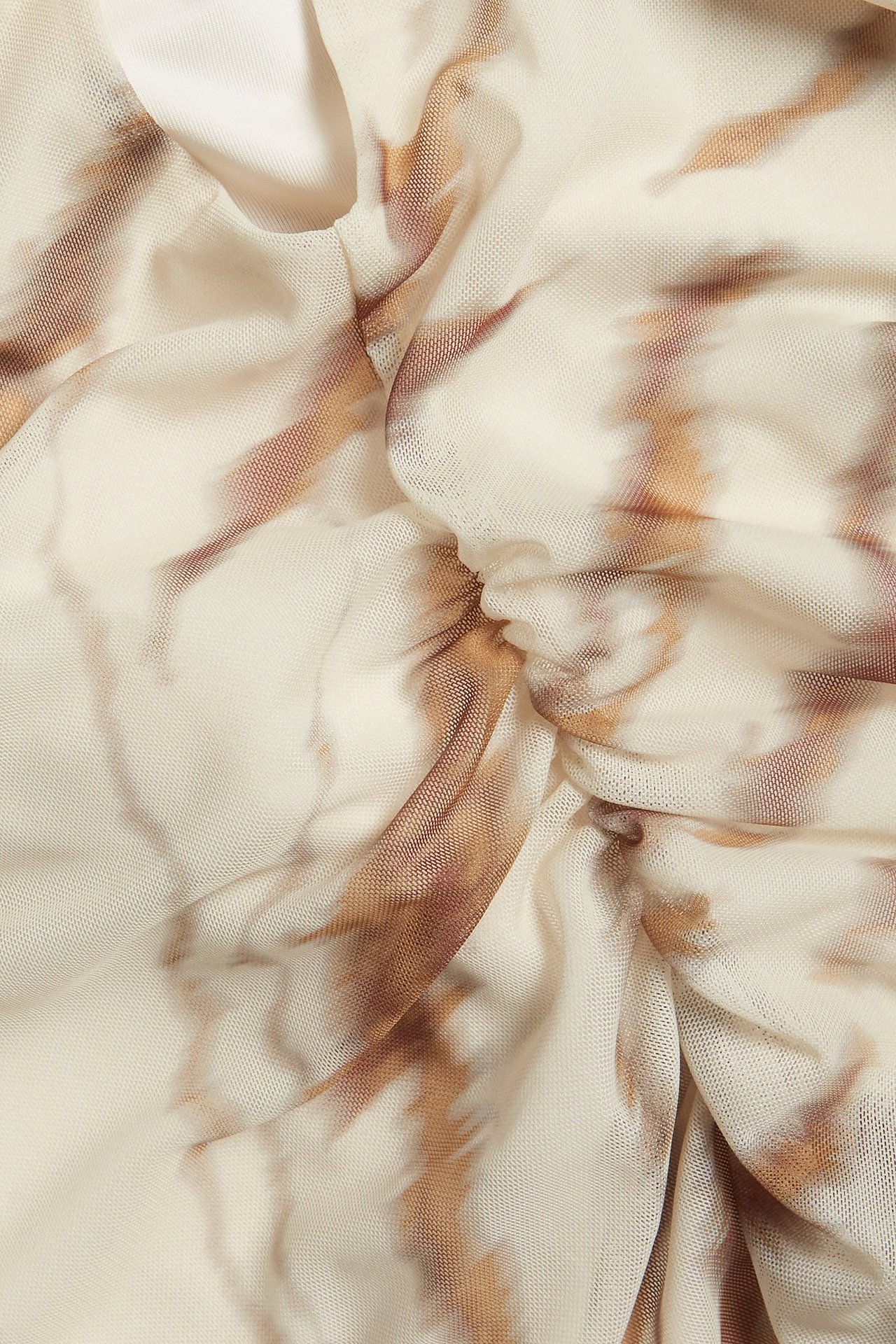 Zbliżenie beżowego wzorzystego topu z siateczki z brązowymi odcieniami i marszczeniami.