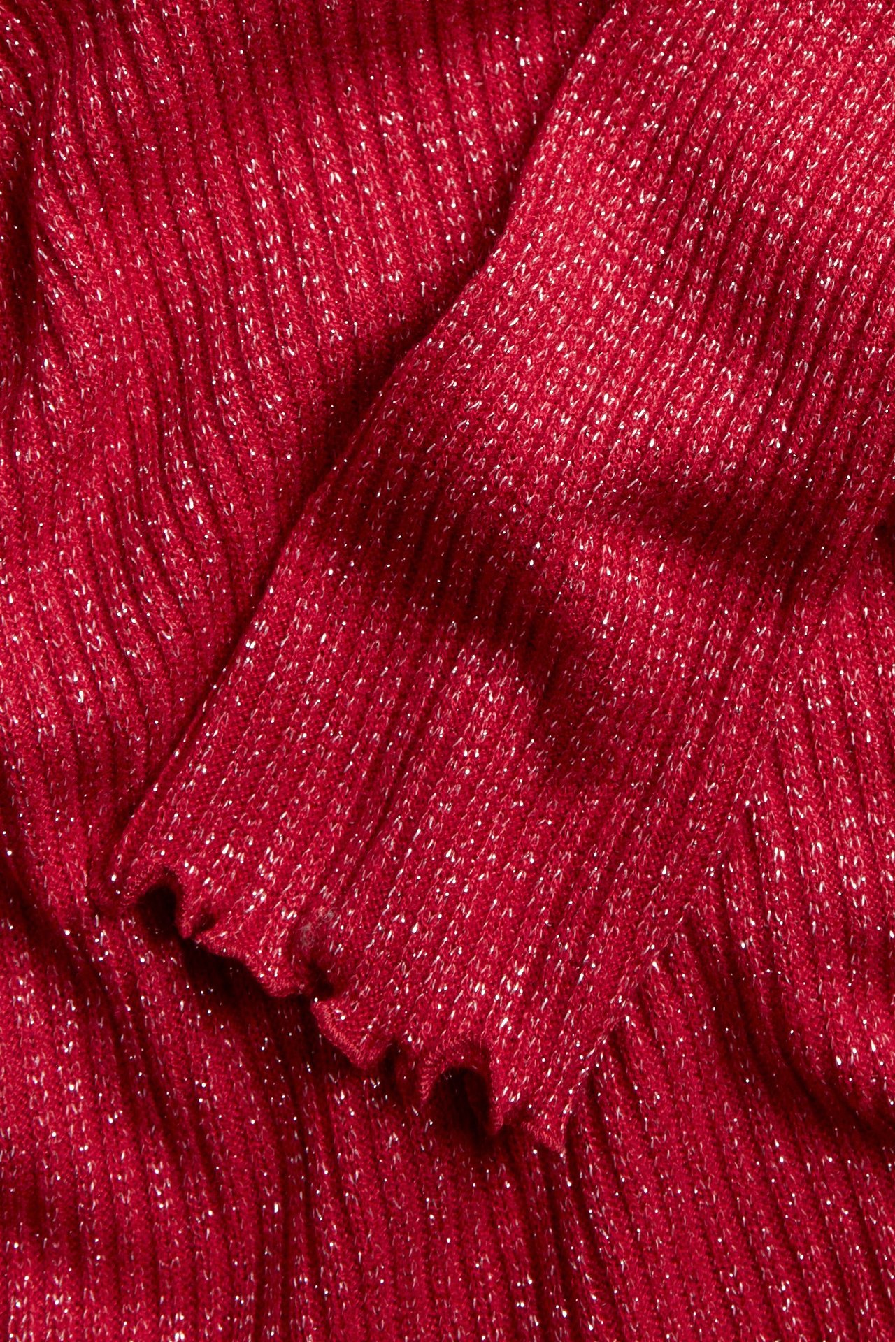 Zbliżenie czerwonego, brokatowego, prążkowanego topu z falbankami.